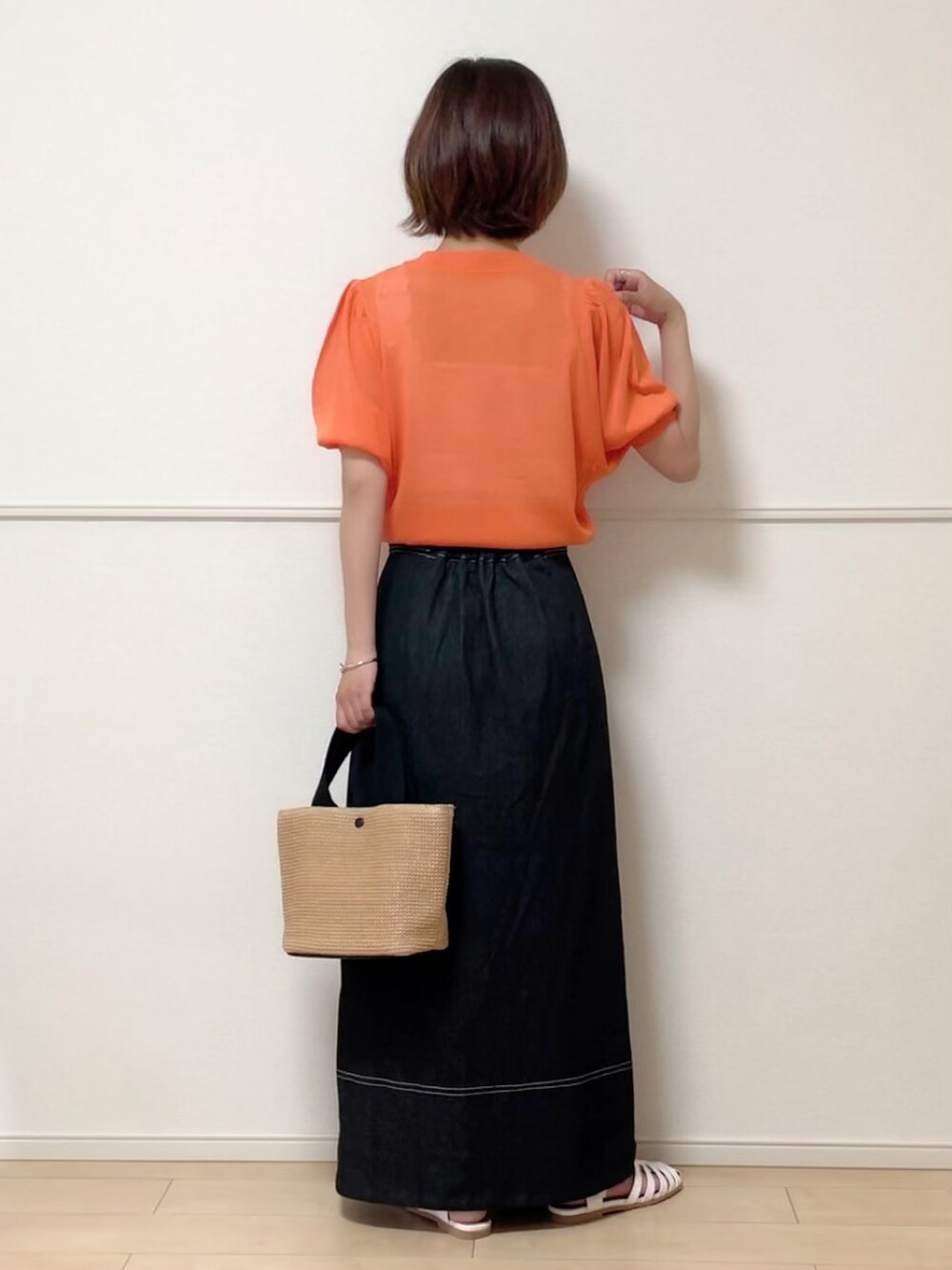 オレンジ系のニット/セーター、ホワイト系のキャミソール、ブラック系のデニムスカートを着用したレディースの夏コーディネートの2枚目の写真