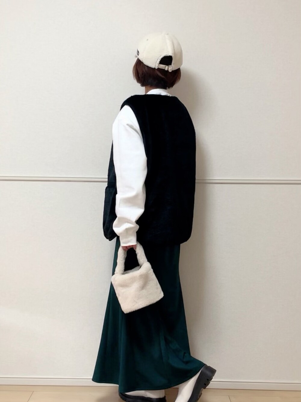 ホワイト系のスウェット、ブラック系のベスト、グリーン系のスカートを着用したレディースの秋コーディネートの2枚目の写真