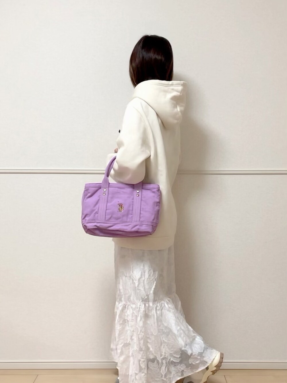 パープル系のトートバッグ、ベージュ系のパーカー、ホワイト系のスカートを着用したレディースの冬コーディネートの2枚目の写真