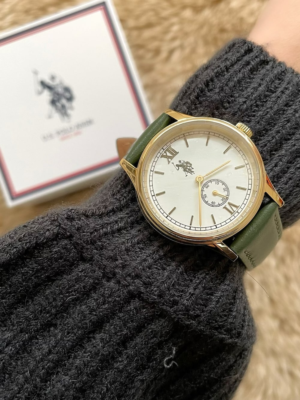 グレー系のワンピース、ブラック系のブーツ、グリーン系のアナログ腕時計を着用したレディースの冬コーディネートの3枚目の写真