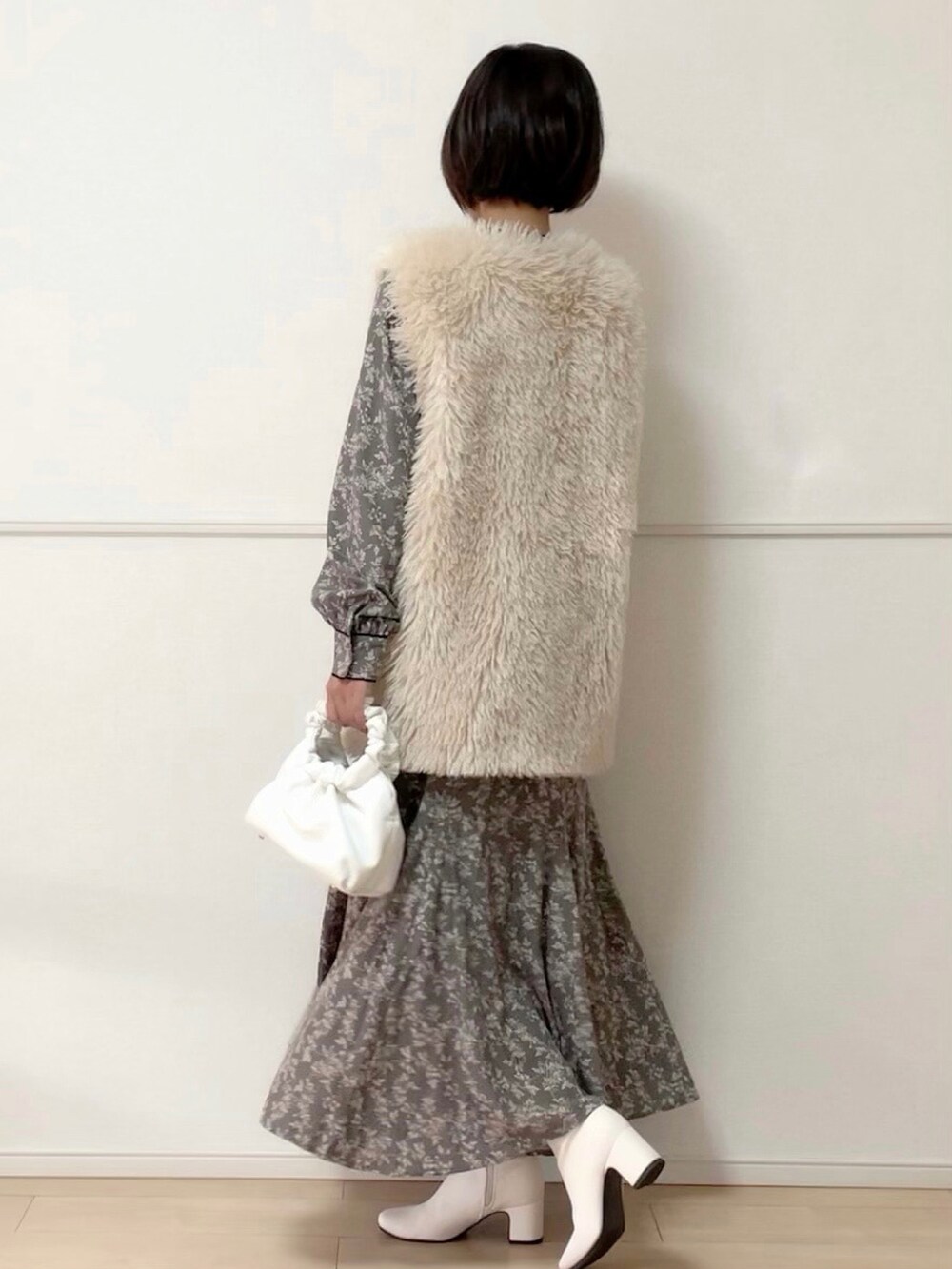 ホワイト系のベスト、グレー系のワンピース、ホワイト系のブーツを着用したレディースの秋コーディネートの2枚目の写真