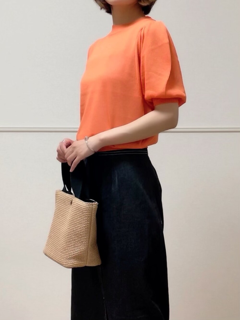 オレンジ系のニット/セーター、ホワイト系のキャミソール、ブラック系のデニムスカートを着用したレディースの夏コーディネートの3枚目の写真