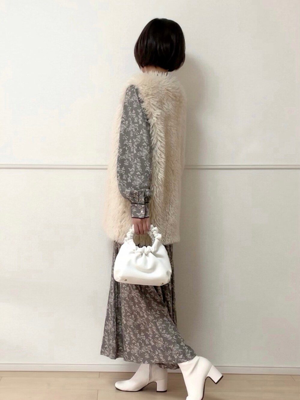 ホワイト系のベスト、グレー系のワンピース、ホワイト系のブーツを着用したレディースの秋コーディネートの3枚目の写真