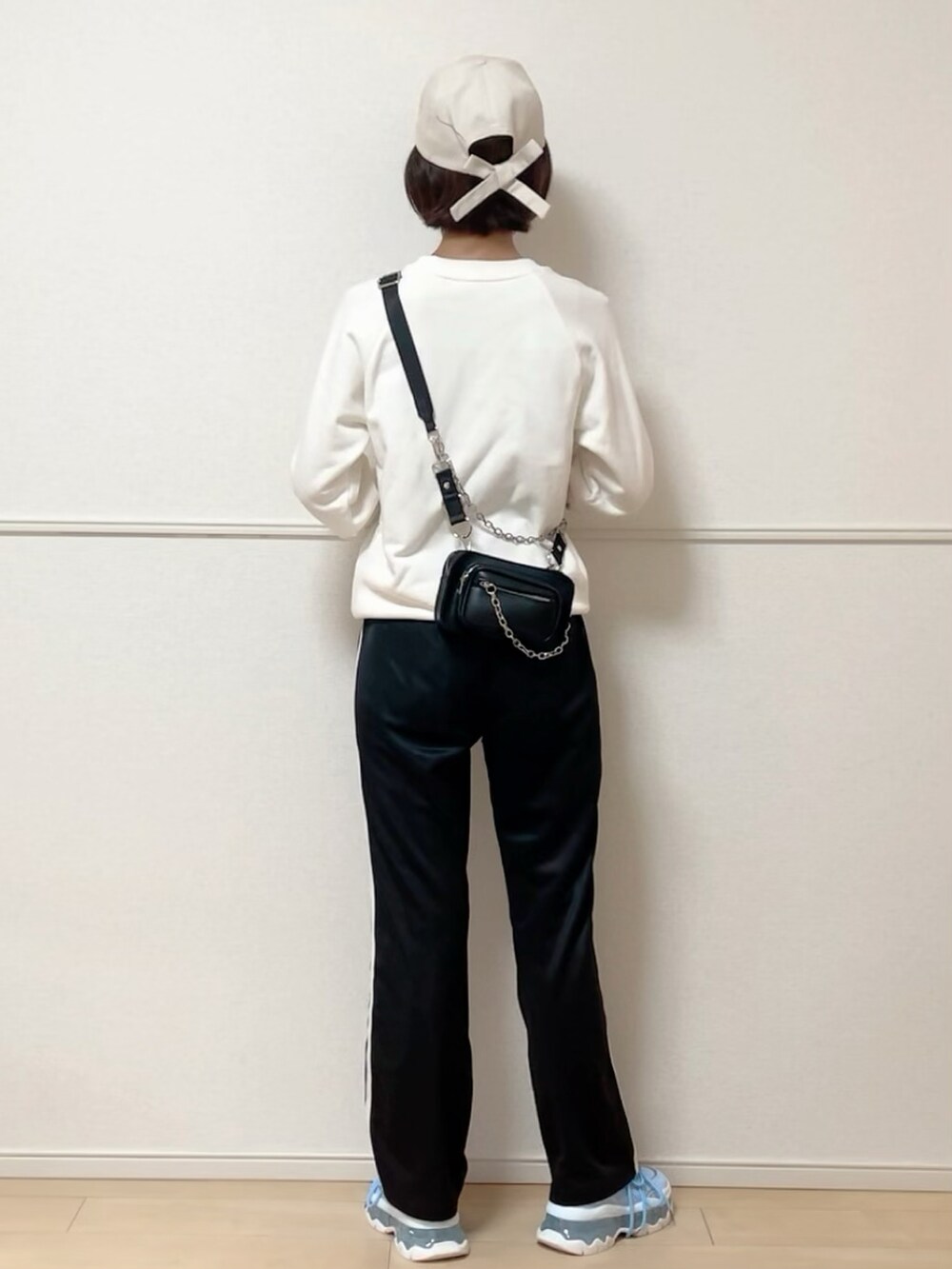 ホワイト系のスウェット、ブラック系のボディバッグ/ウエストポーチ、ベージュ系のキャップを着用したレディースの秋コーディネートの2枚目の写真