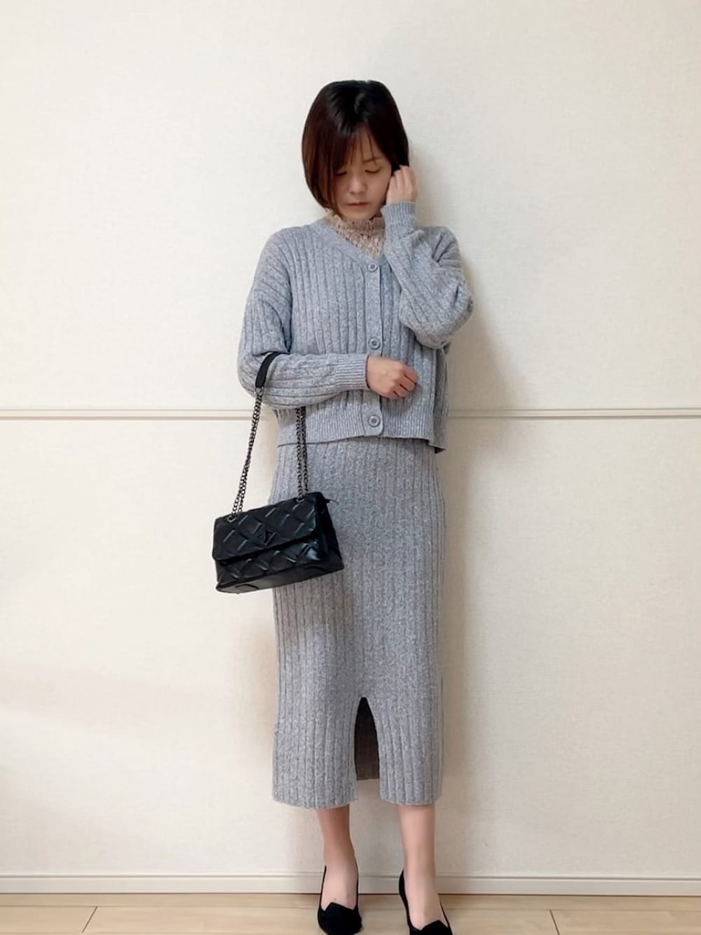 ブラック系のショルダーバッグ、ホワイト系のトップス、グレー系のワンピースを着用したレディースの春コーディネートの2枚目の写真