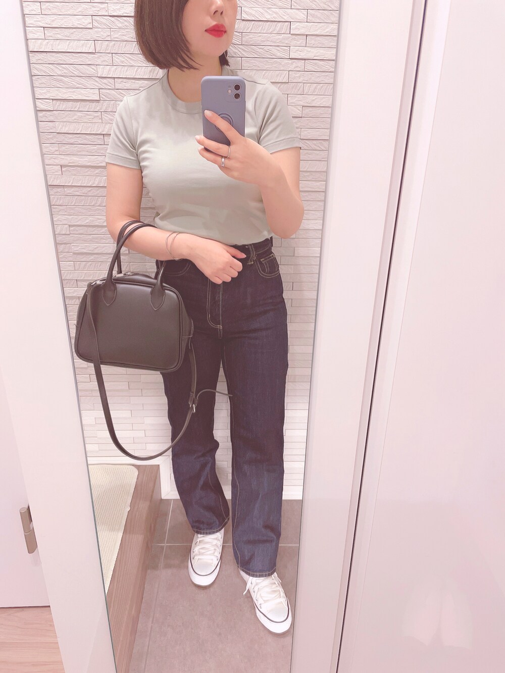 グリーン系のTシャツ/カットソー、ブラック系のボストンバッグ、ブルー系のデニムパンツを着用したレディースの春コーディネートの2枚目の写真