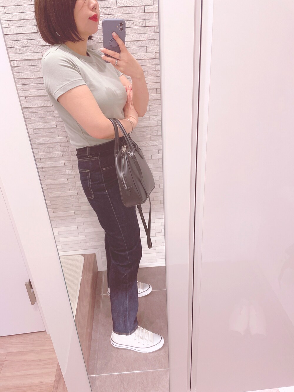 グリーン系のTシャツ/カットソー、ブラック系のボストンバッグ、ブルー系のデニムパンツを着用したレディースの春コーディネートの3枚目の写真