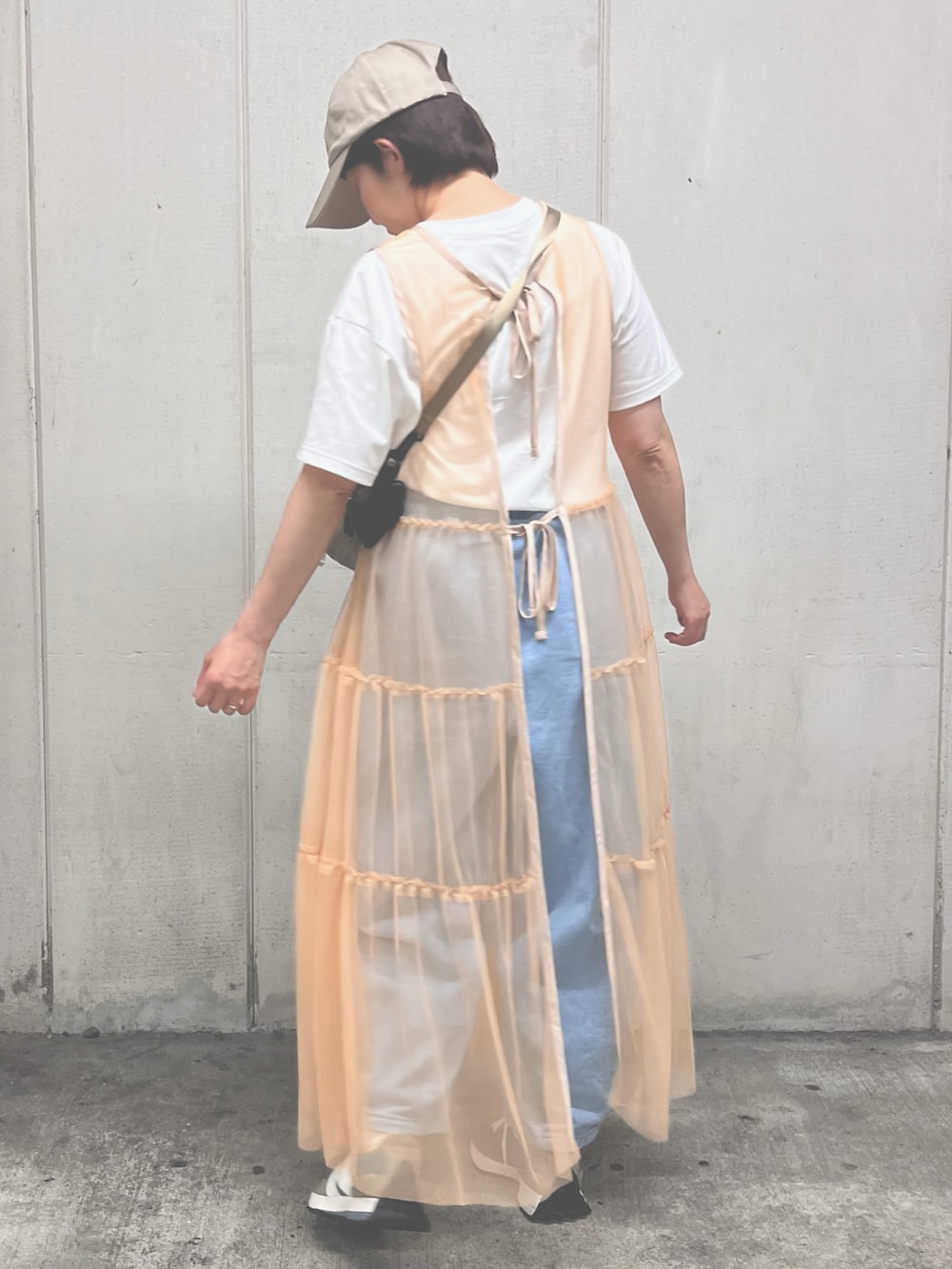ブルー系のデニムパンツ、グレー系のショルダーバッグ、オレンジ系のワンピースを着用したレディースの春コーディネートの2枚目の写真