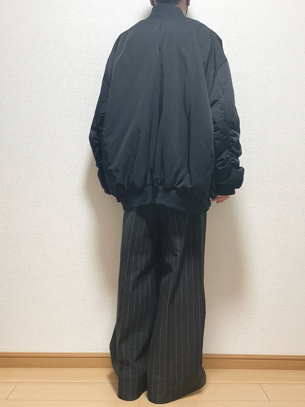 ブラック系のMA-1、ベージュ系のニット/セーター、ブラック系のパンツを着用したメンズの冬コーディネートの4枚目の写真