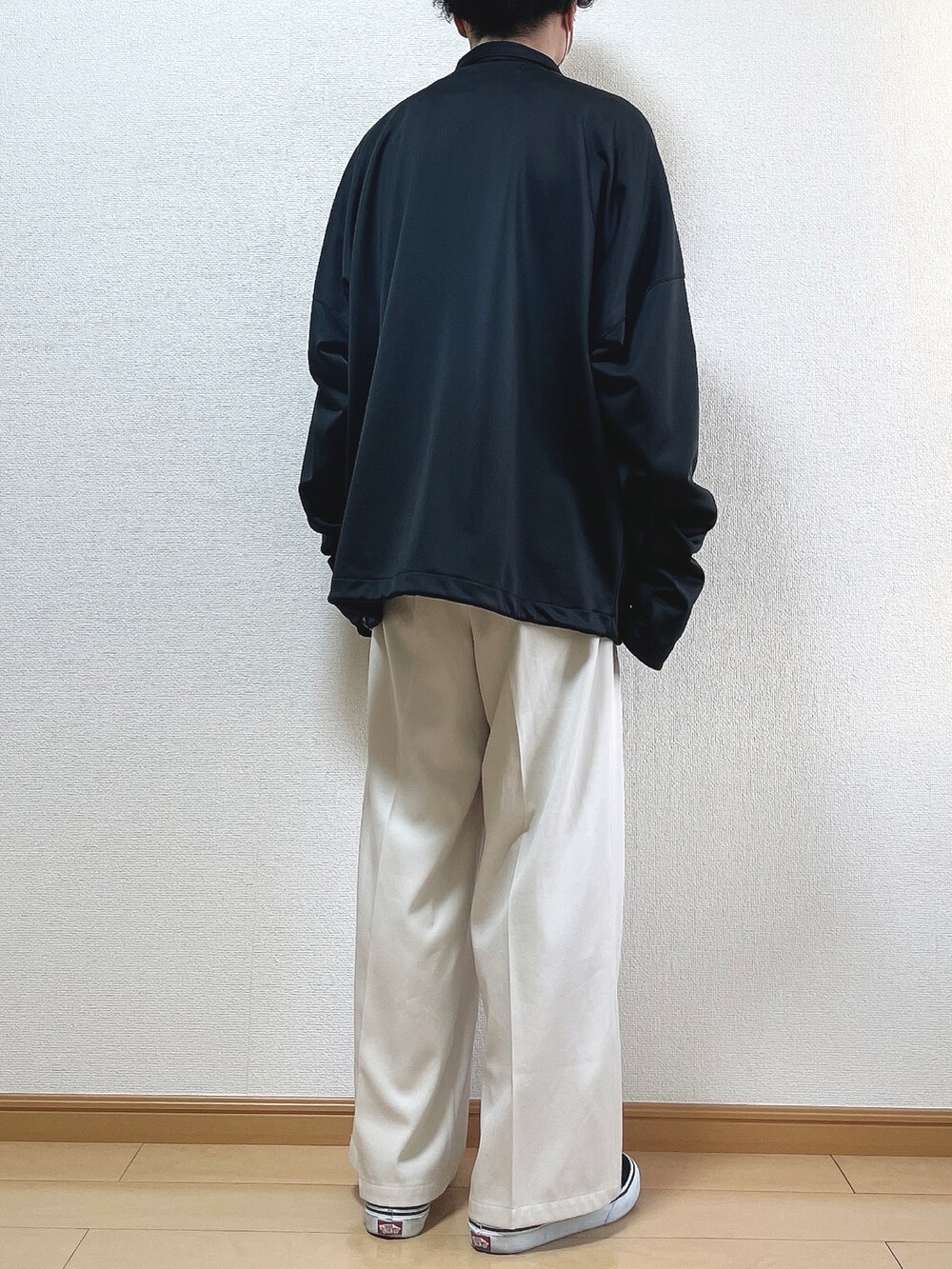 ブラック系のブルゾン、ブラック系のTシャツ/カットソー、ベージュ系のスラックスを着用したメンズの冬コーディネートの4枚目の写真