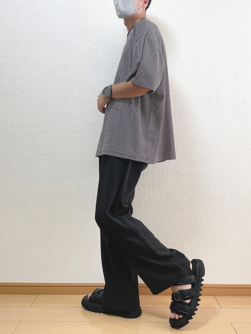 グレー系のTシャツ/カットソー、ブラック系のスラックス、ブラック系のサンダルを着用したメンズの秋コーディネートの3枚目の写真