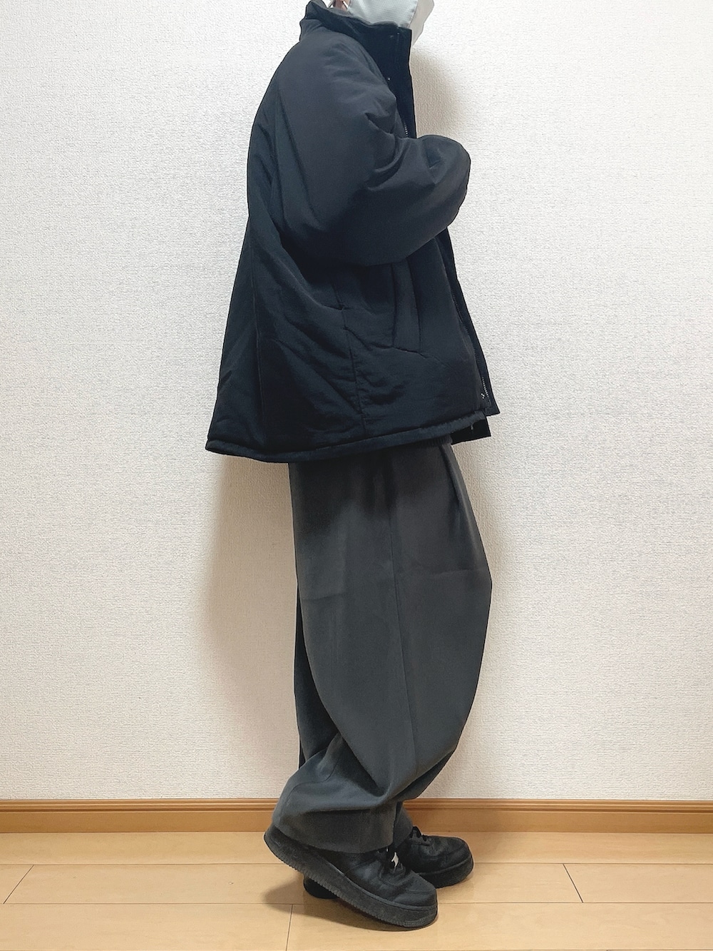 ブラック系のその他アウター、グレー系のニット/セーター、グレー系のスラックスを着用したメンズの冬コーディネートの2枚目の写真