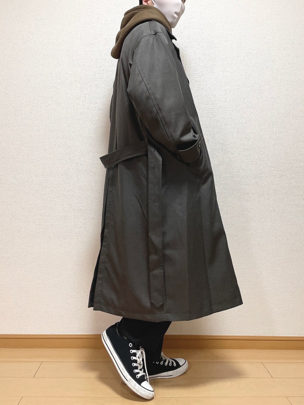 グレー系のトレンチコート、ブラウン系のパーカー、ブラック系のスラックスを着用したメンズの冬コーディネートの3枚目の写真