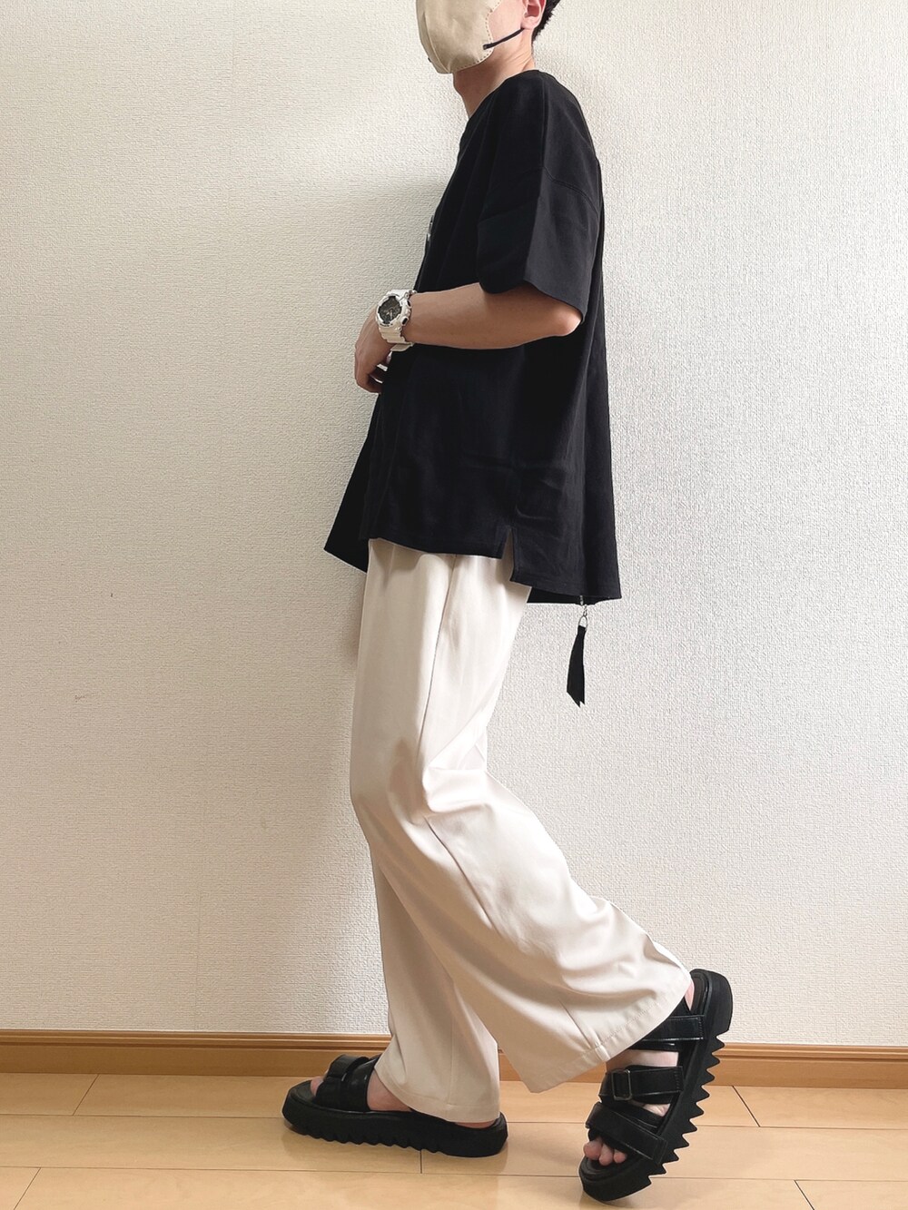 ブラック系のTシャツ/カットソー、ベージュ系のスラックス、ブラック系のサンダルを着用したメンズの夏コーディネートの3枚目の写真