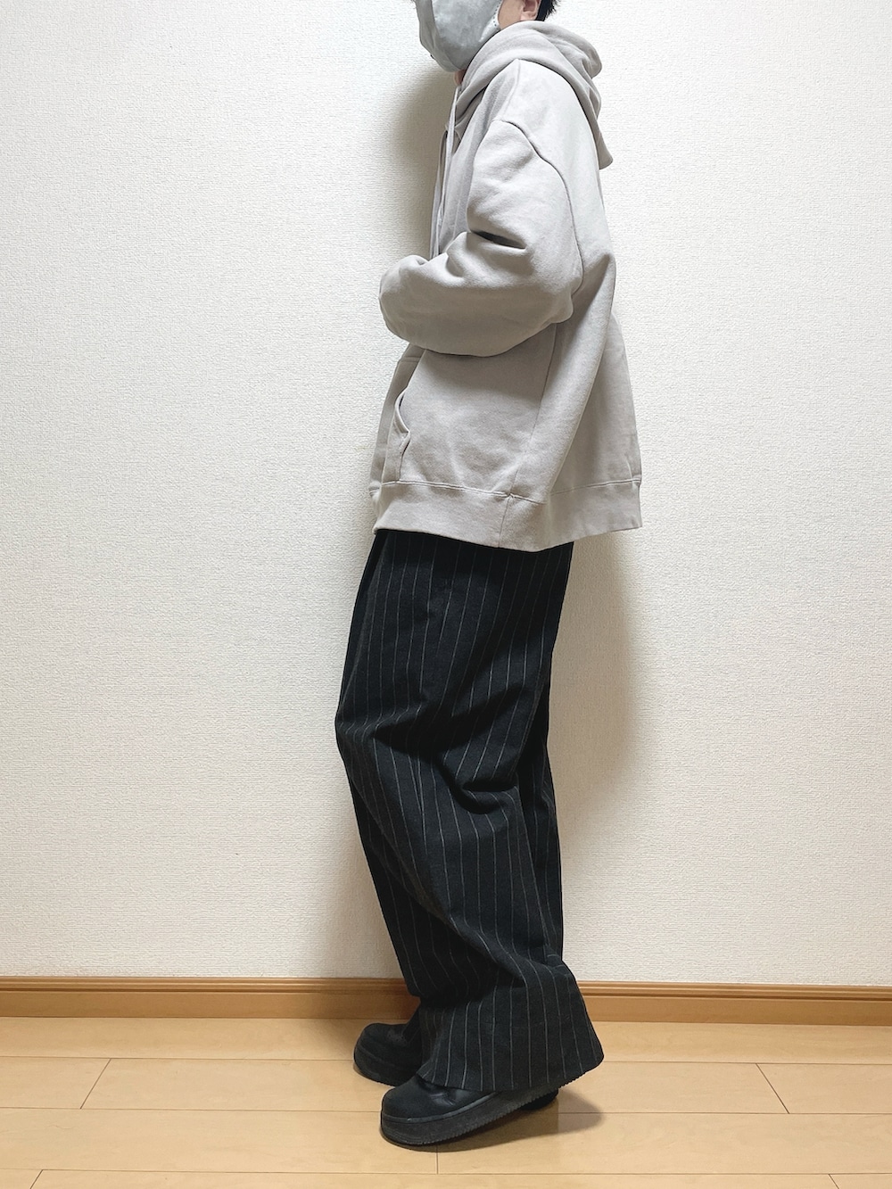 グレー系のパーカー、ブラック系のパンツ、ブラック系のスニーカーを着用したメンズの秋コーディネートの3枚目の写真