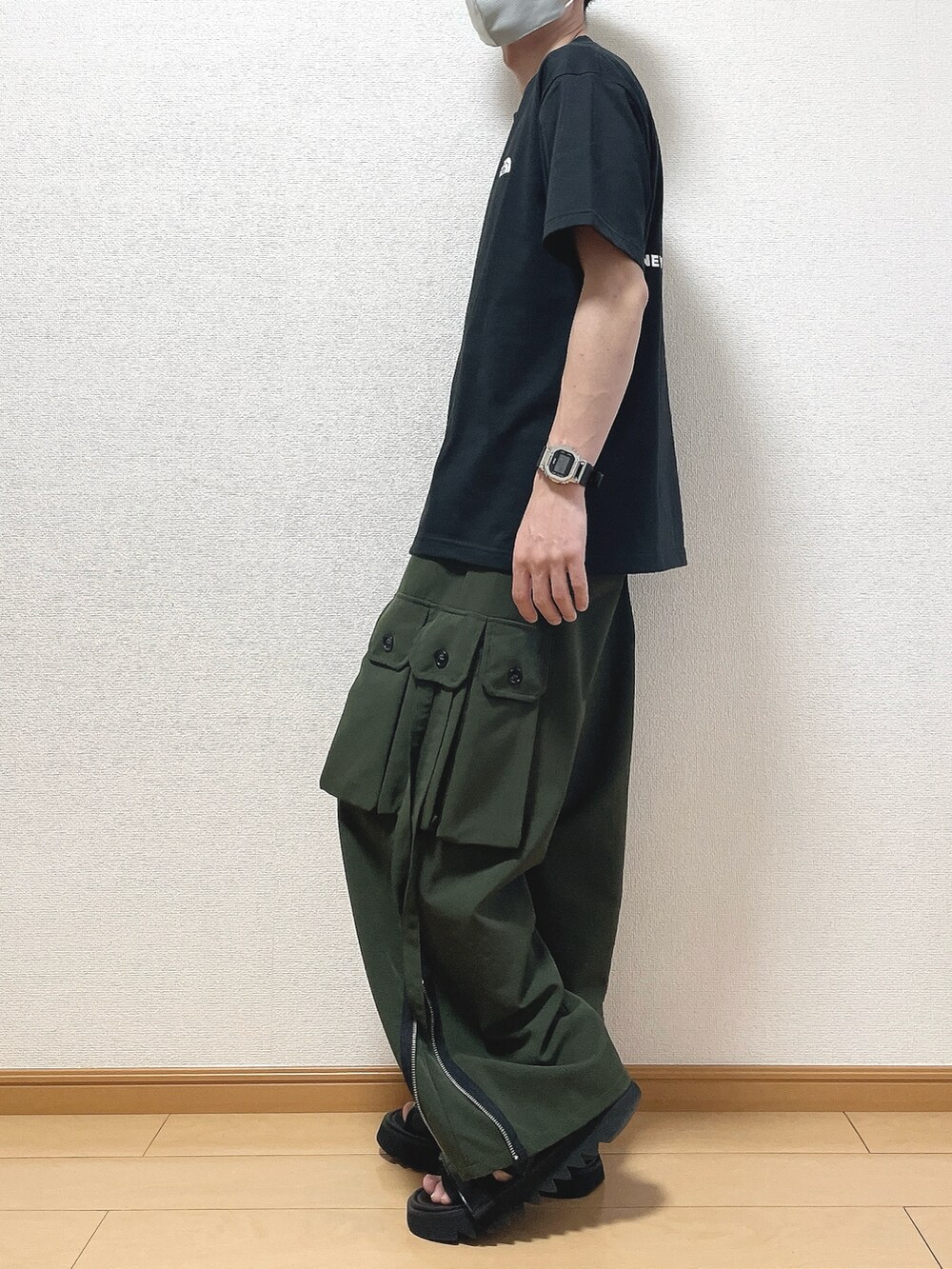 ブラック系のTシャツ/カットソー、グリーン系のカーゴパンツ、ブラック系のサンダルを着用したメンズの春コーディネートの3枚目の写真