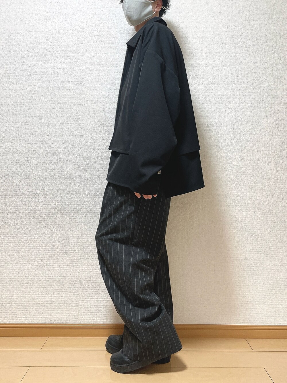 ブラック系のブルゾン、ホワイト系のTシャツ/カットソー、ブラック系のパンツを着用したメンズの春コーディネートの3枚目の写真