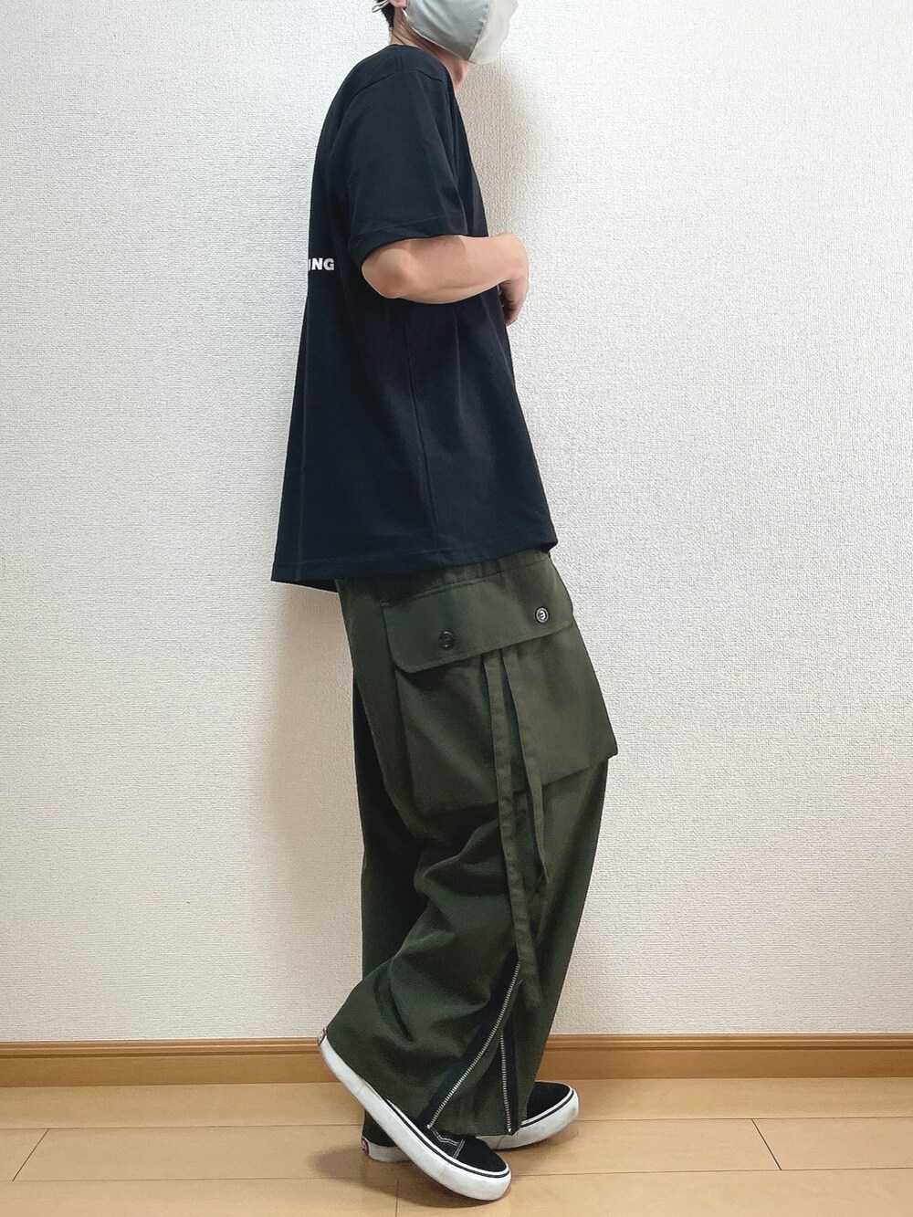 ブラック系のTシャツ/カットソー、グリーン系のカーゴパンツ、ブラック系のスニーカーを着用したメンズの秋コーディネートの2枚目の写真