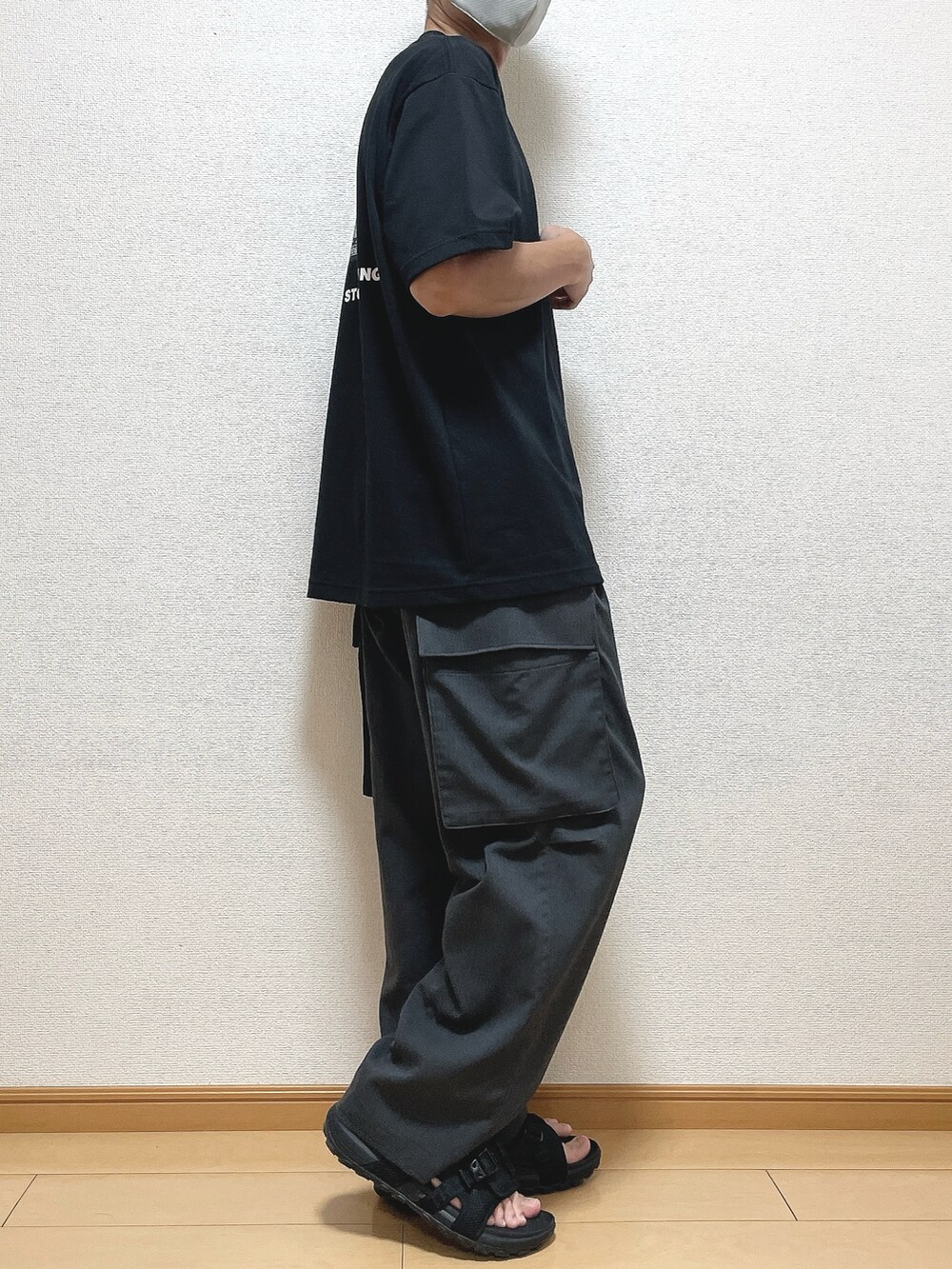 ブラック系のTシャツ/カットソー、グレー系のカーゴパンツ、ブラック系のサンダルを着用したメンズの夏コーディネートの2枚目の写真