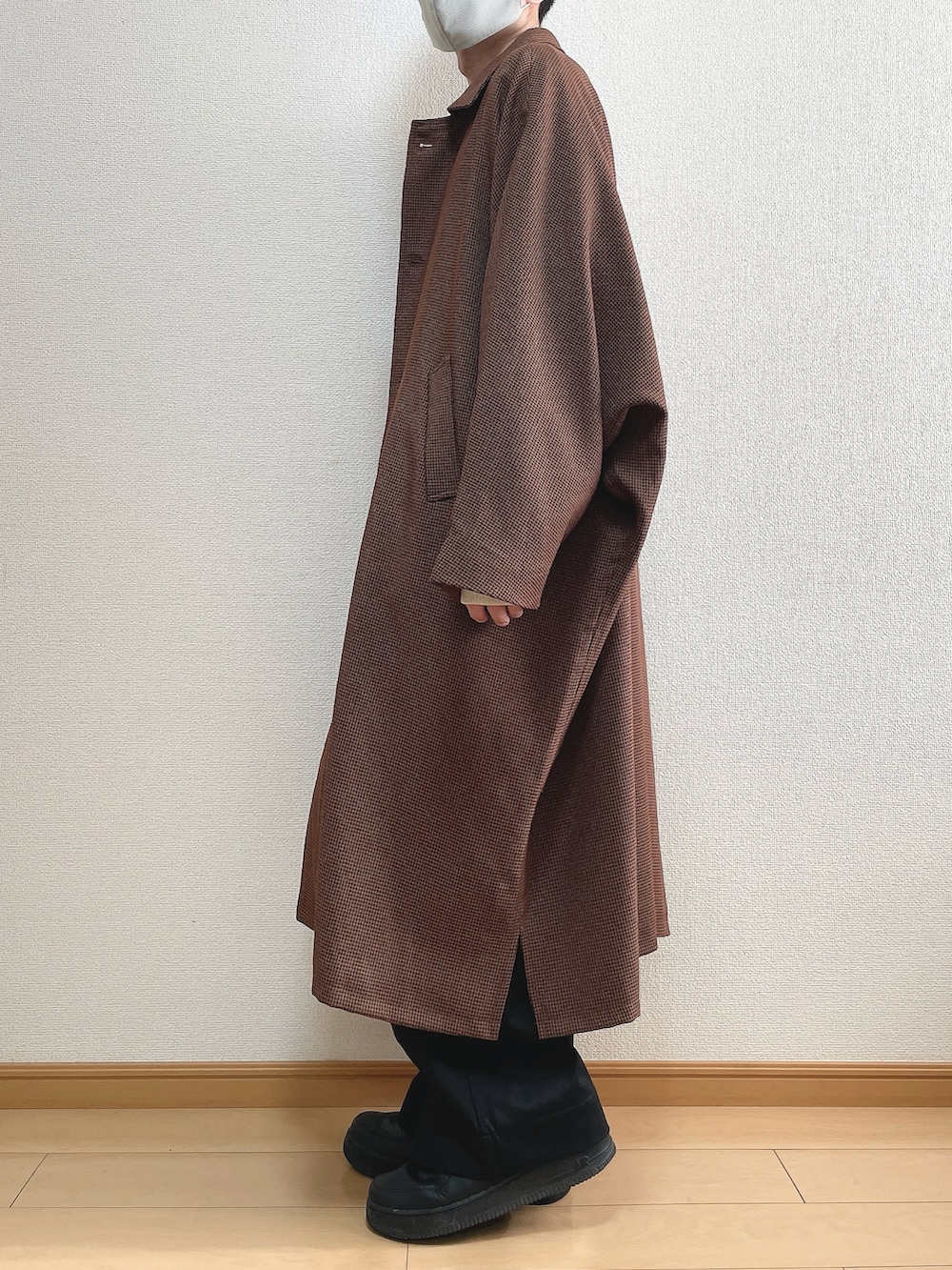 ブラウン系のステンカラーコート、ホワイト系のニット/セーター、ブラック系のスラックスを着用したメンズの冬コーディネートの3枚目の写真