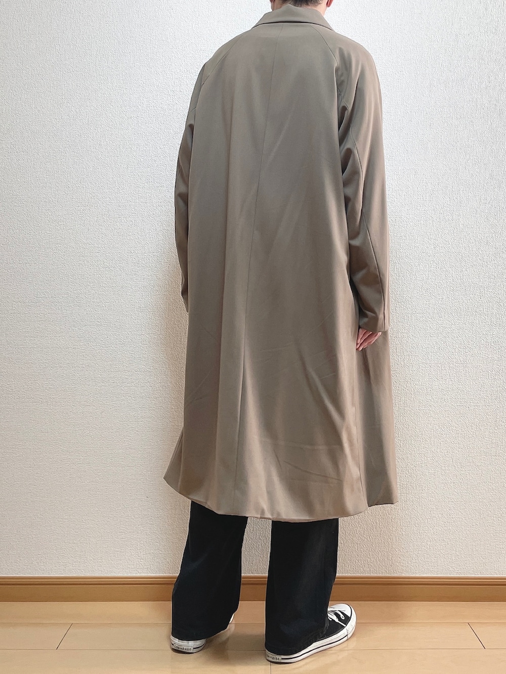 ベージュ系のステンカラーコート、グリーン系のTシャツ/カットソー、ブラック系のデニムパンツを着用したメンズの冬コーディネートの4枚目の写真