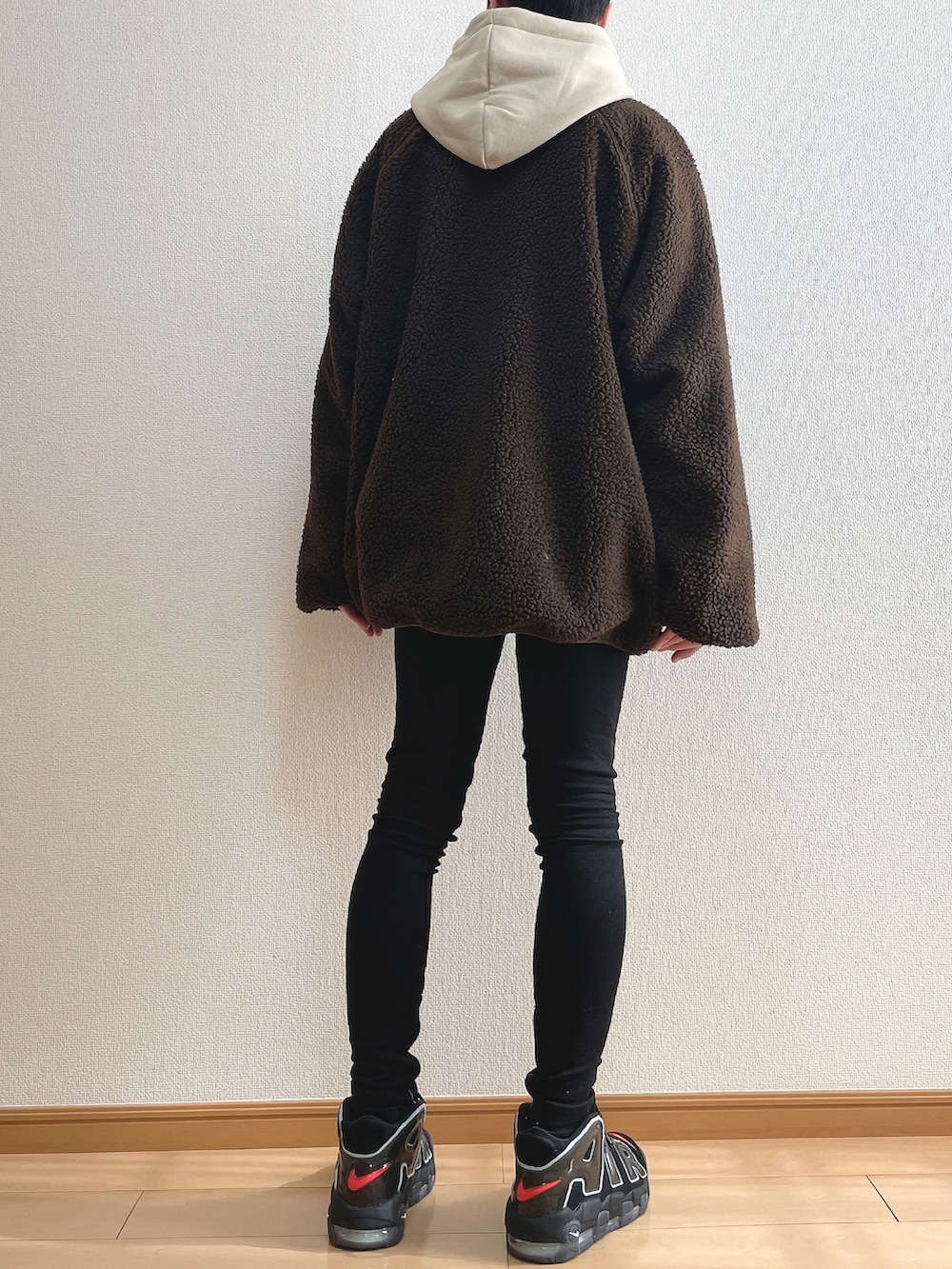 ブラウン系のブルゾン、ベージュ系のパーカー、ブラック系のデニムパンツを着用したメンズの冬コーディネートの4枚目の写真