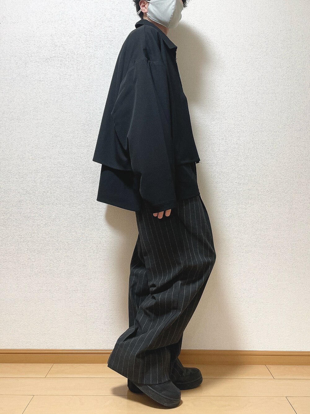 ブラック系のブルゾン、ホワイト系のTシャツ/カットソー、ブラック系のパンツを着用したメンズの春コーディネートの2枚目の写真