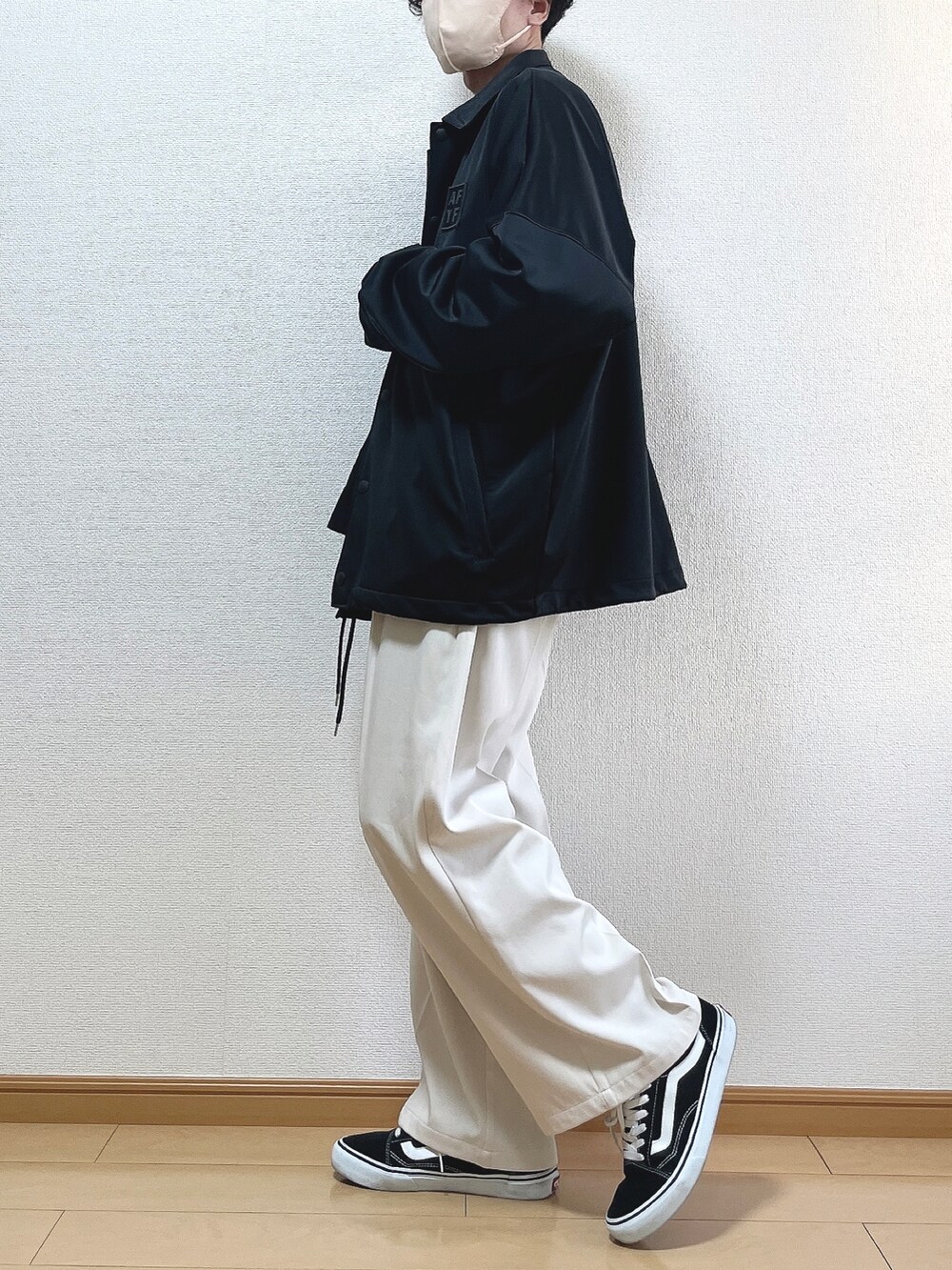 ブラック系のブルゾン、ブラック系のTシャツ/カットソー、ベージュ系のスラックスを着用したメンズの冬コーディネートの3枚目の写真