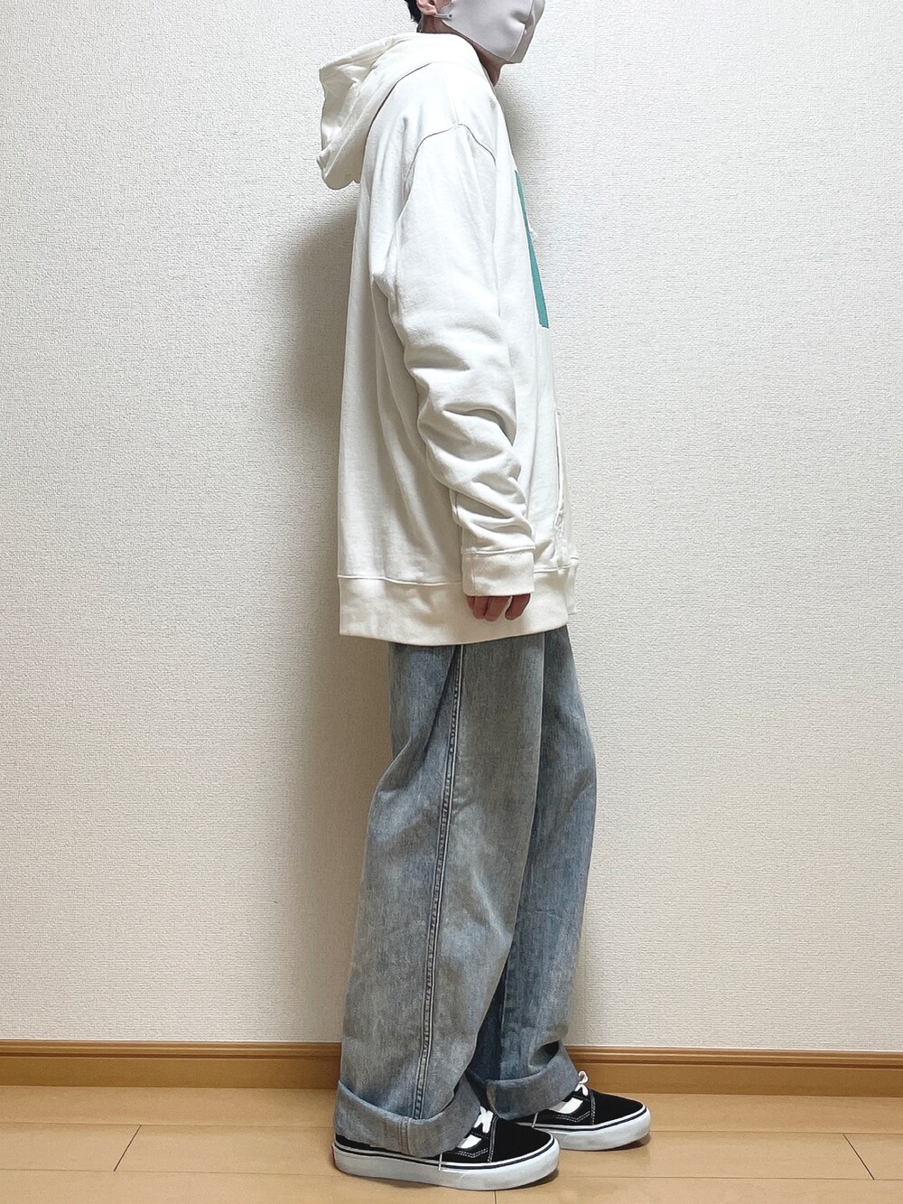ホワイト系のパーカー、ブルー系のデニムパンツ、ブラック系のスニーカーを着用したメンズの春コーディネートの2枚目の写真