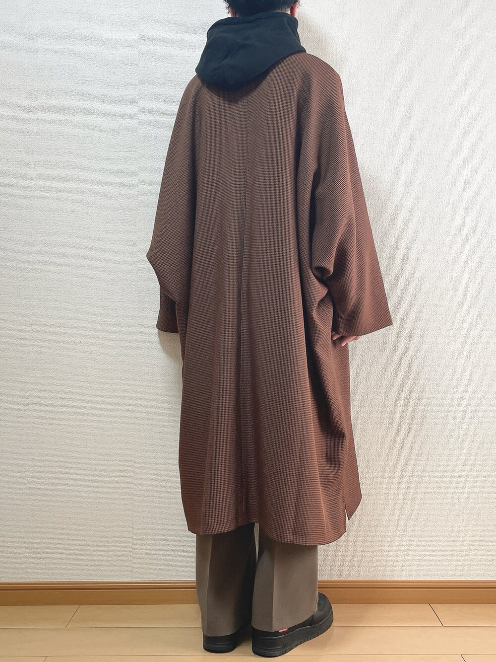 ブラウン系のステンカラーコート、ブラック系のパーカー、ブラウン系のその他パンツを着用したメンズの春コーディネートの4枚目の写真