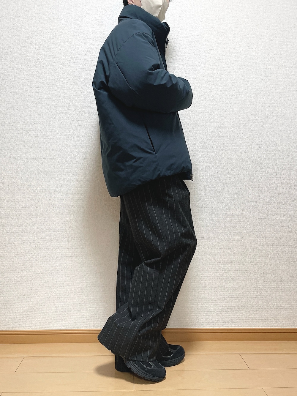 グレー系のダウンジャケット/コート、ベージュ系のニット/セーター、ブラック系のパンツを着用したメンズの冬コーディネートの2枚目の写真