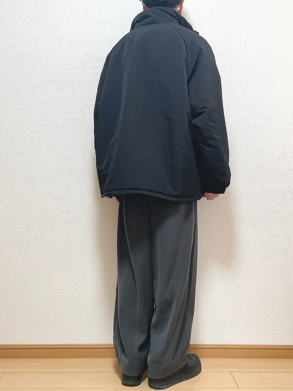 ブラック系のその他アウター、グレー系のニット/セーター、グレー系のスラックスを着用したメンズの冬コーディネートの4枚目の写真