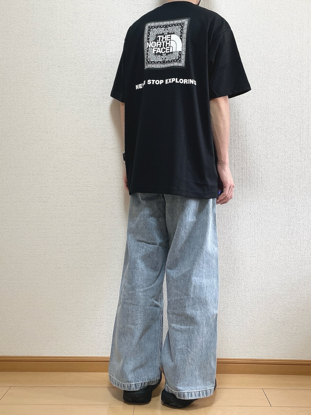 ブラック系のTシャツ/カットソー、ブルー系のデニムパンツ、ブラック系のサンダルを着用したメンズの夏コーディネートの4枚目の写真