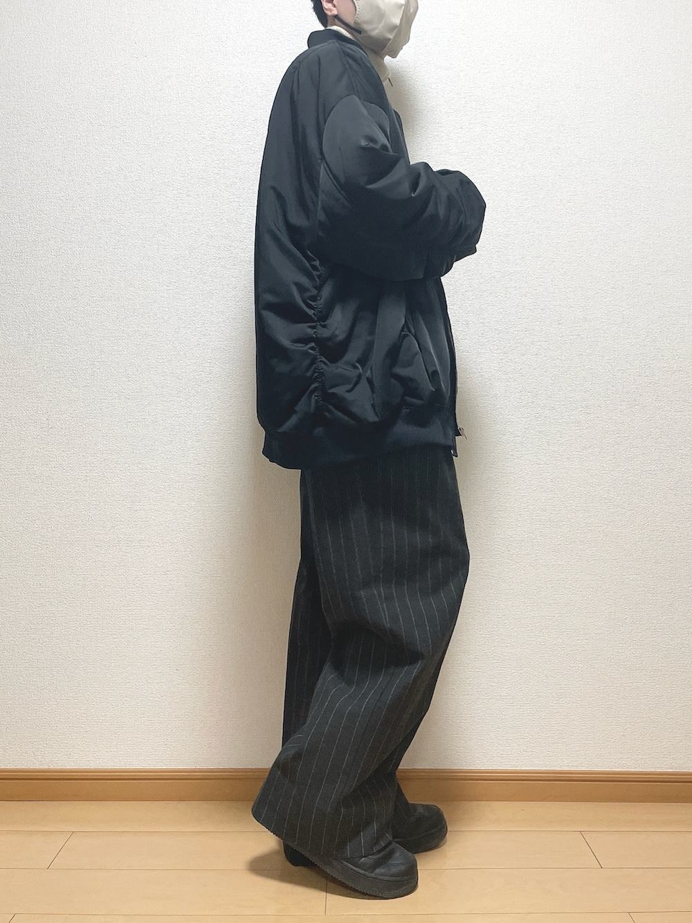 ブラック系のMA-1、ベージュ系のニット/セーター、ブラック系のパンツを着用したメンズの冬コーディネートの2枚目の写真