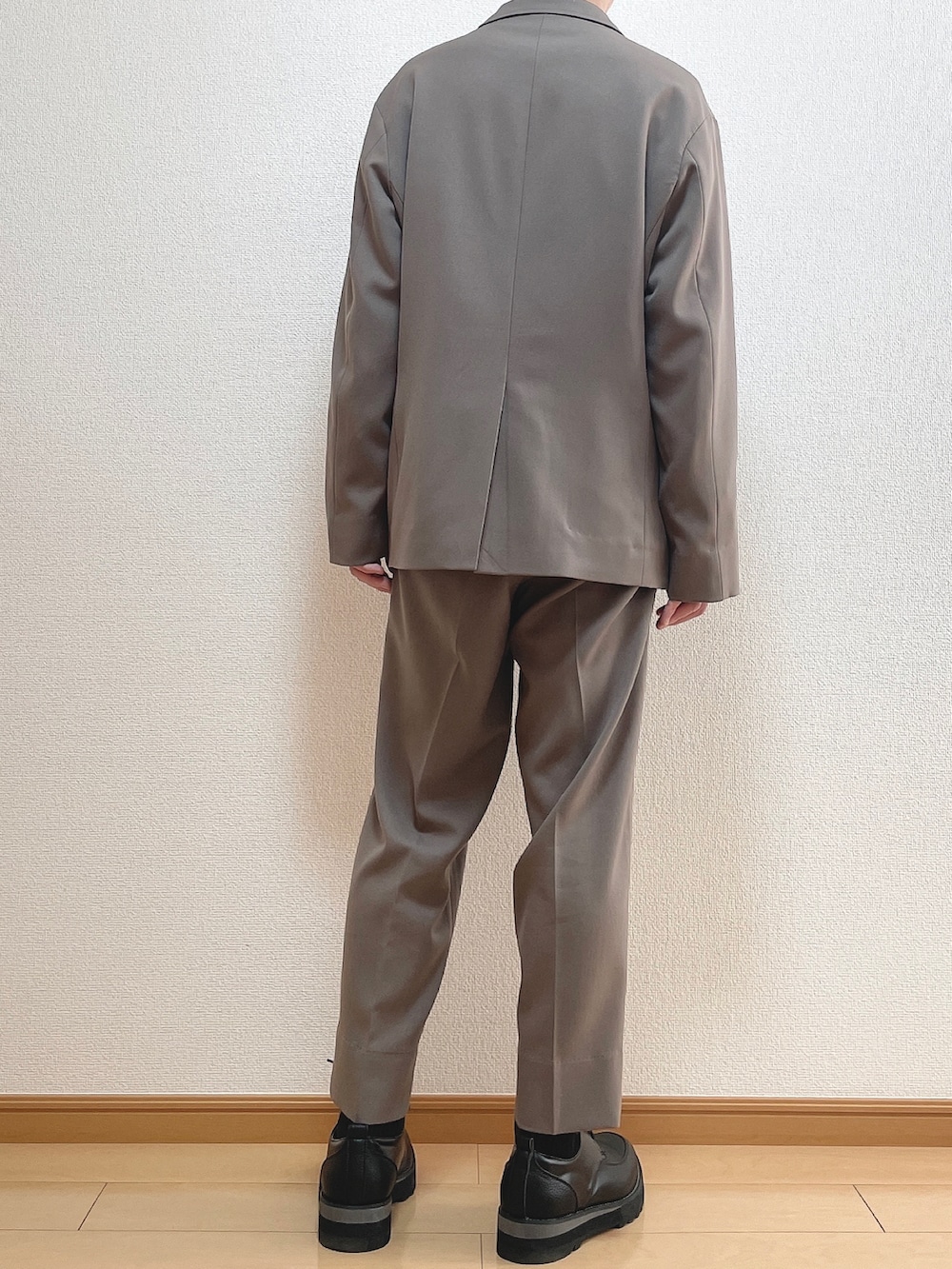 ベージュ系のセットアップ、ホワイト系のTシャツ/カットソー、ブラック系のドレスシューズを着用したメンズの冬コーディネートの4枚目の写真