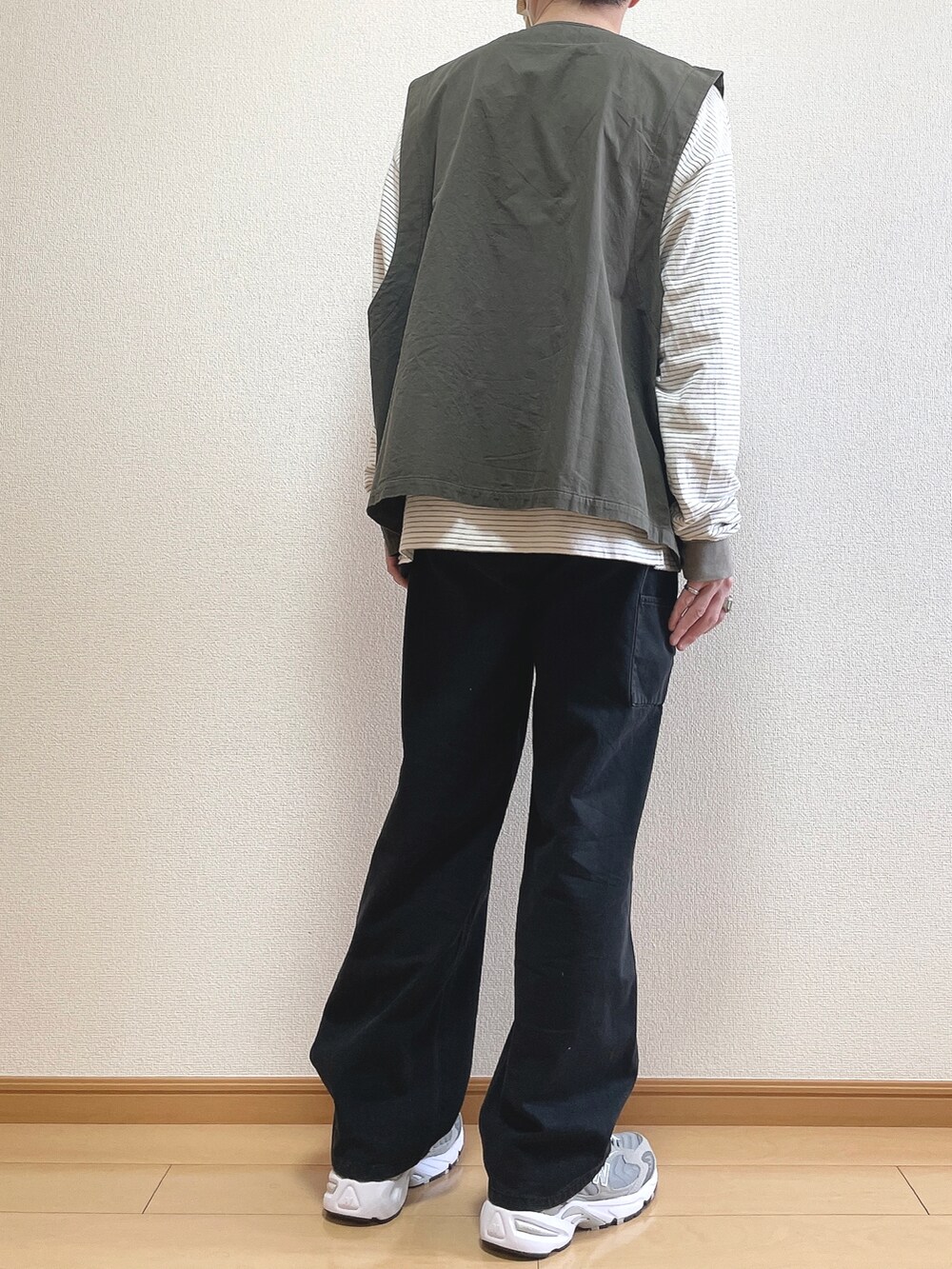 グレー系のベスト、グリーン系のTシャツ/カットソー、ブラック系のデニムパンツを着用したメンズの春コーディネートの4枚目の写真