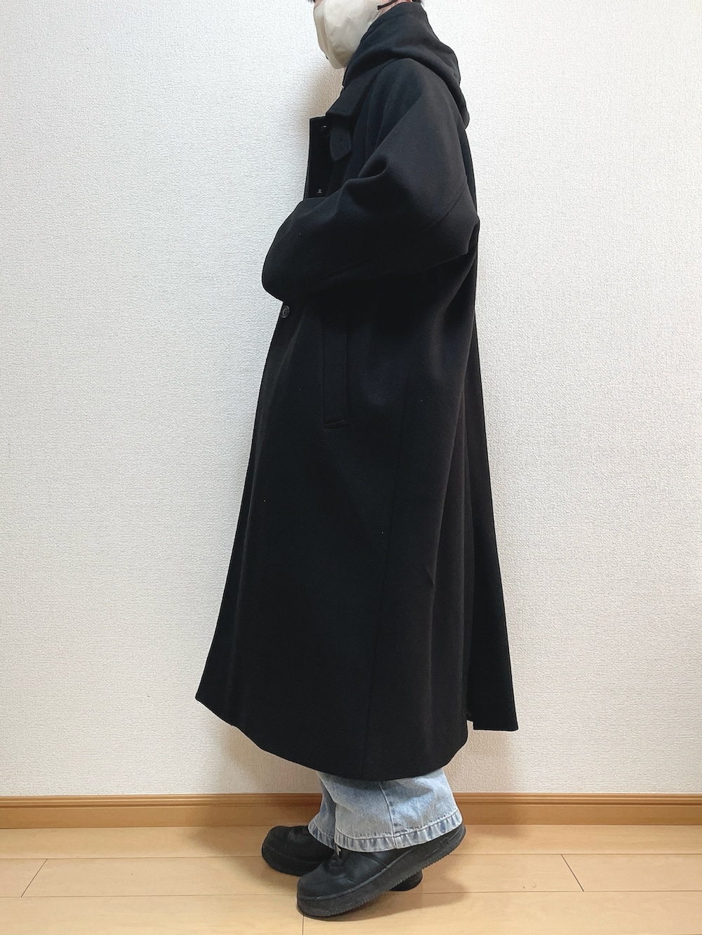 ブラック系のステンカラーコート、ブラック系のパーカー、ブルー系のデニムパンツを着用したメンズの冬コーディネートの3枚目の写真