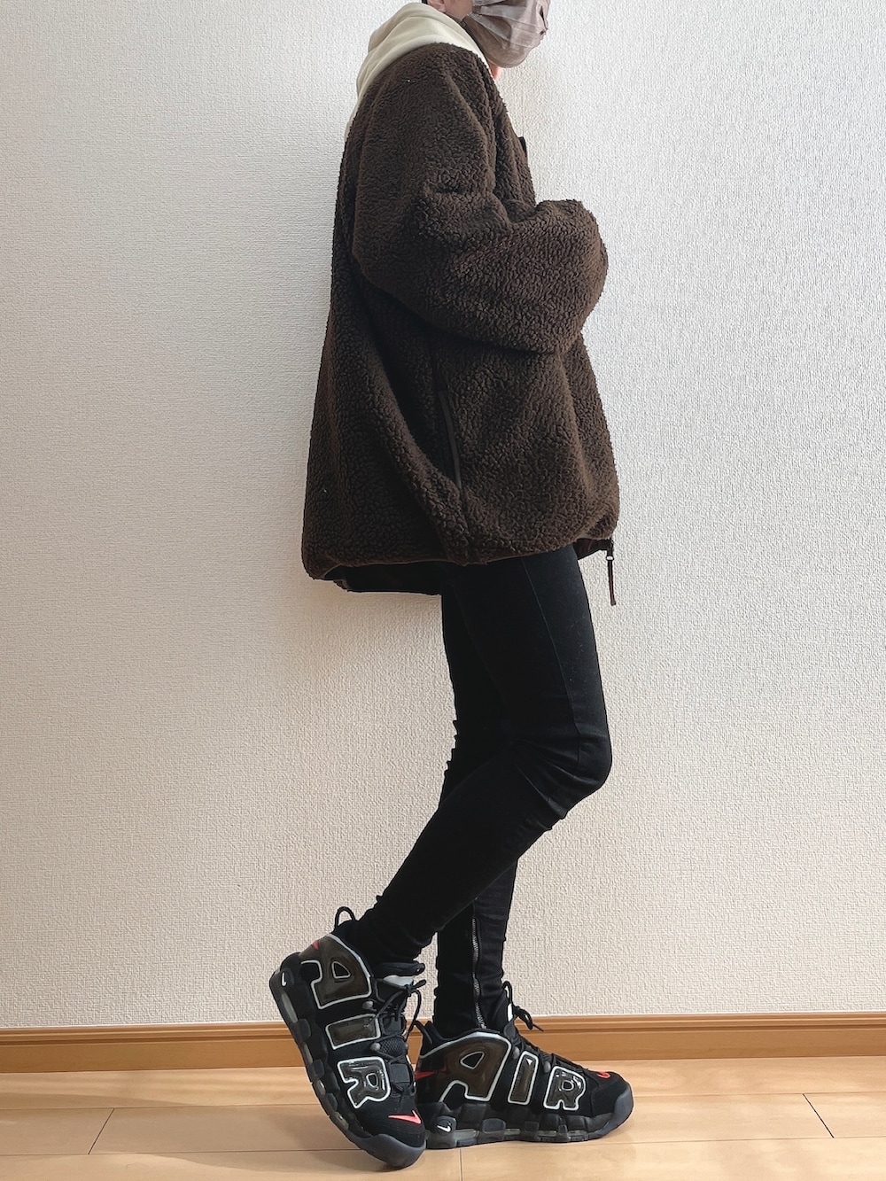 ブラウン系のブルゾン、ベージュ系のパーカー、ブラック系のデニムパンツを着用したメンズの冬コーディネートの2枚目の写真