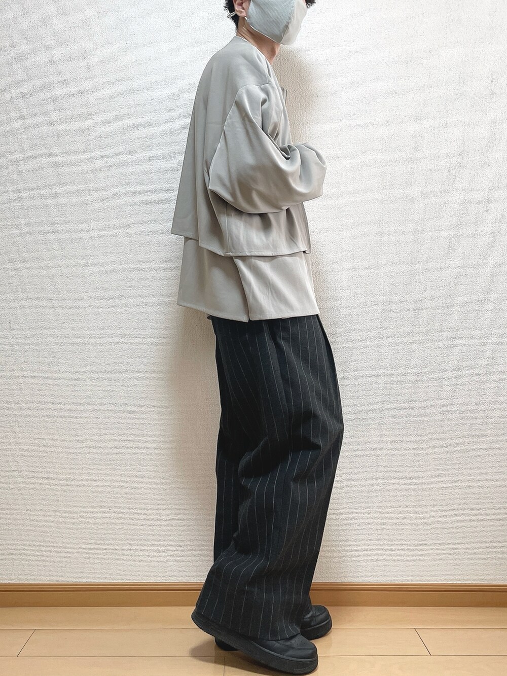 グレー系のブルゾン、ホワイト系のTシャツ/カットソー、ブラック系のパンツを着用したメンズの秋コーディネートの2枚目の写真