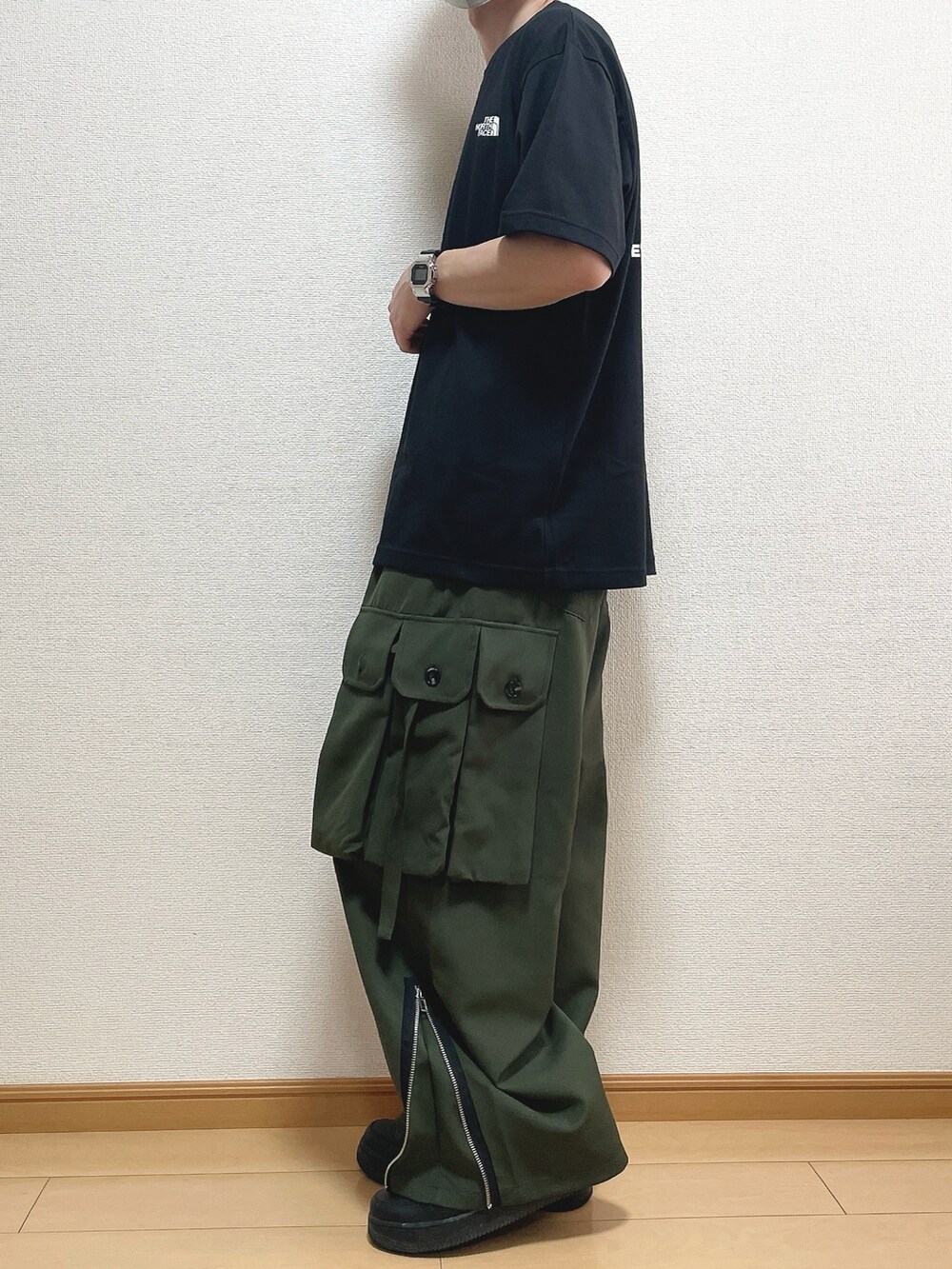 ブラック系のTシャツ/カットソー、グリーン系のカーゴパンツ、ブラック系のスニーカーを着用したメンズの春コーディネートの3枚目の写真