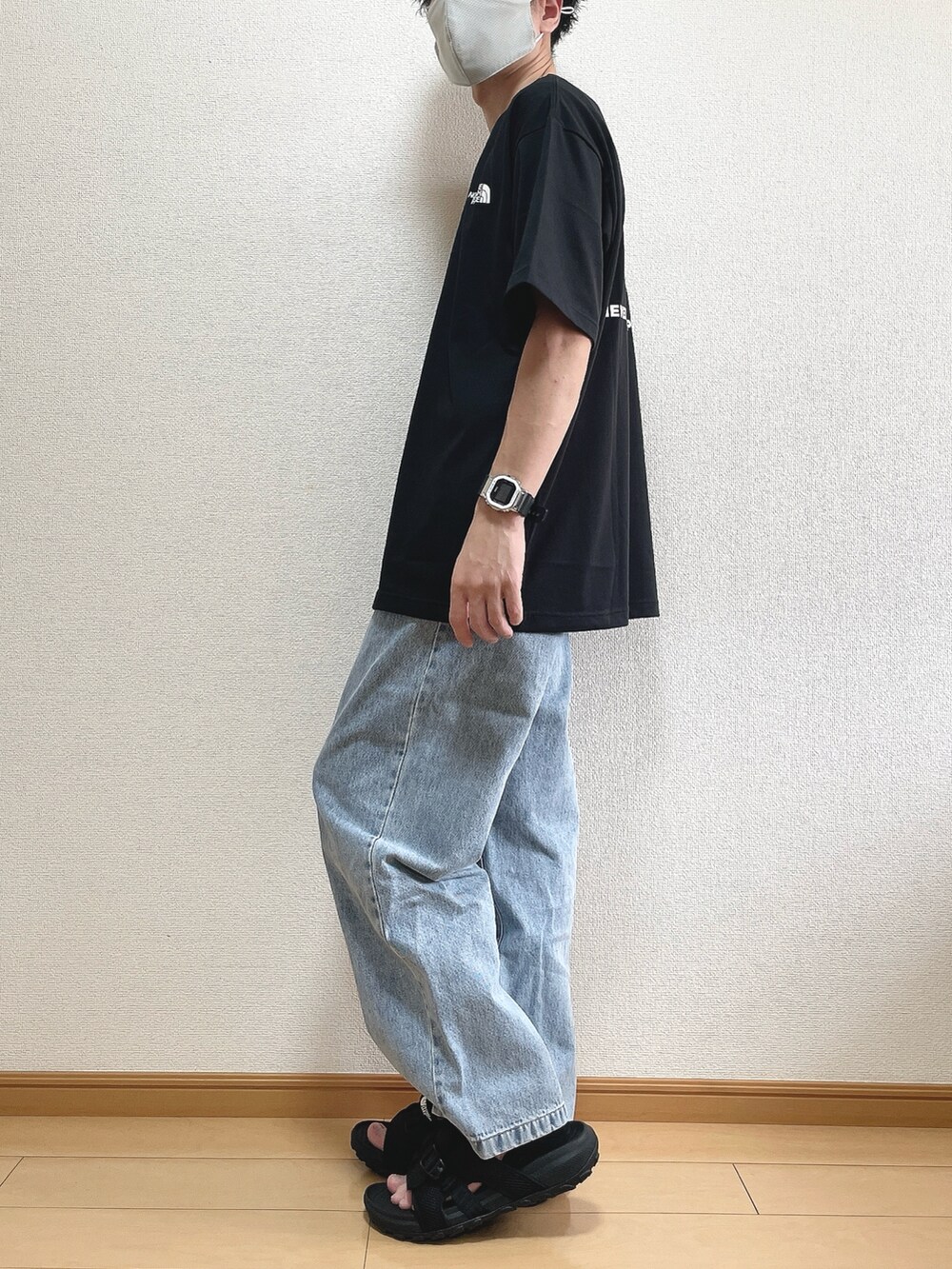 ブラック系のTシャツ/カットソー、ブルー系のデニムパンツ、ブラック系のサンダルを着用したメンズの夏コーディネートの3枚目の写真