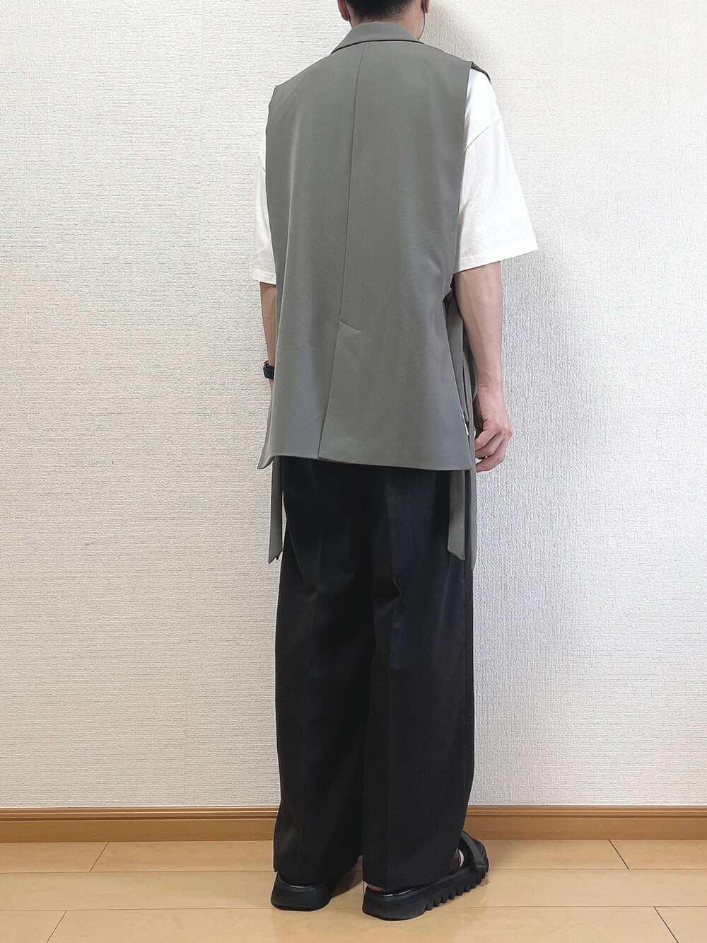 グレー系のベスト、ホワイト系のTシャツ/カットソー、ブラック系のスラックスを着用したメンズの夏コーディネートの4枚目の写真
