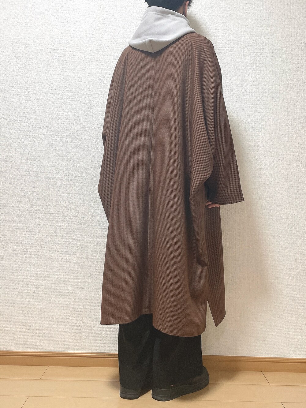 ブラウン系のステンカラーコート、グレー系のパーカー、ブラック系のその他パンツを着用したメンズの冬コーディネートの4枚目の写真