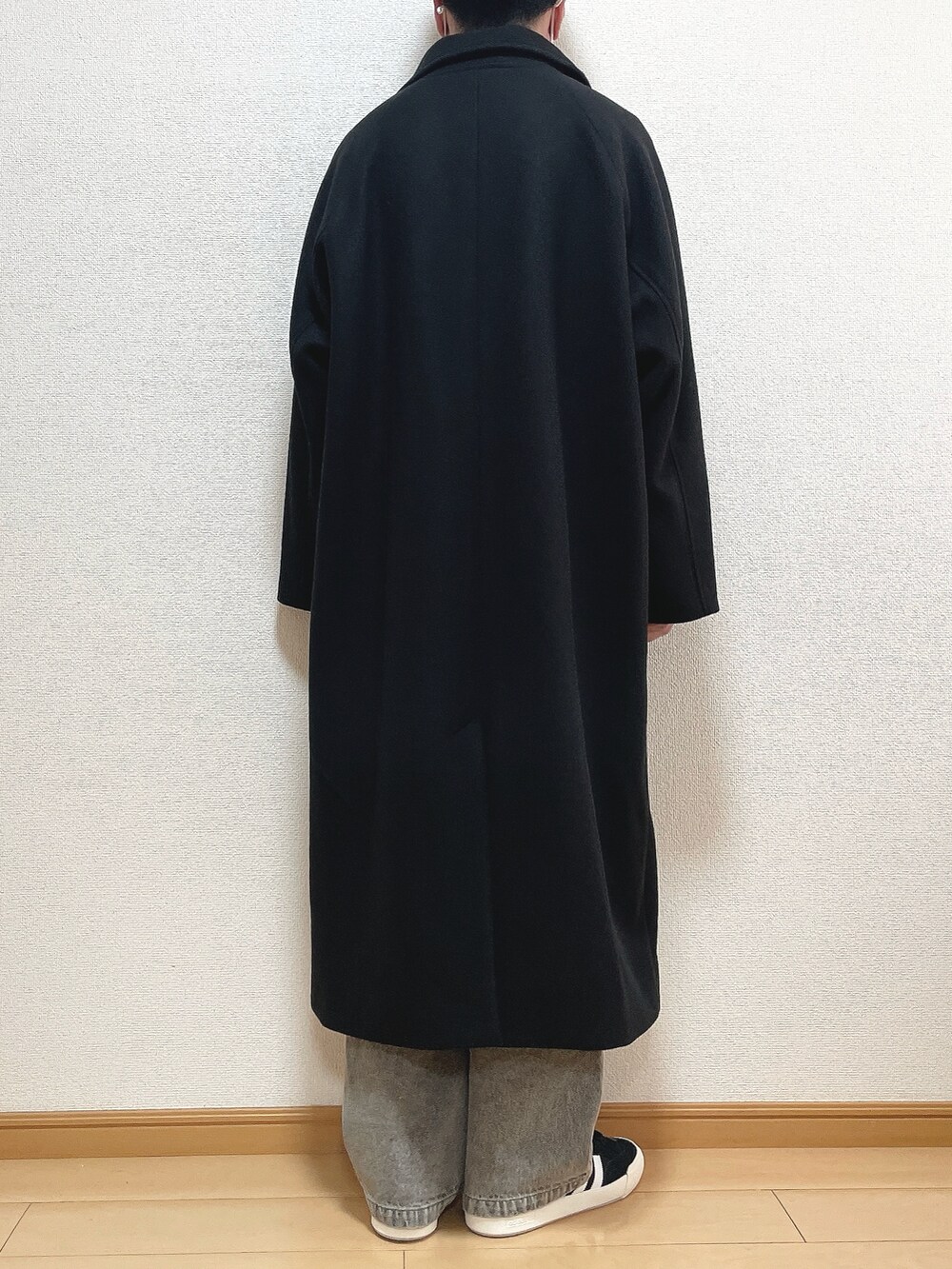 ブラック系のステンカラーコート、ベージュ系のニット/セーター、ブルー系のデニムパンツを着用したメンズの冬コーディネートの4枚目の写真