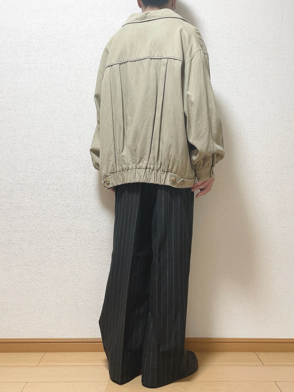 ベージュ系のブルゾン、ホワイト系のTシャツ/カットソー、ブラック系のパンツを着用したメンズの春コーディネートの4枚目の写真