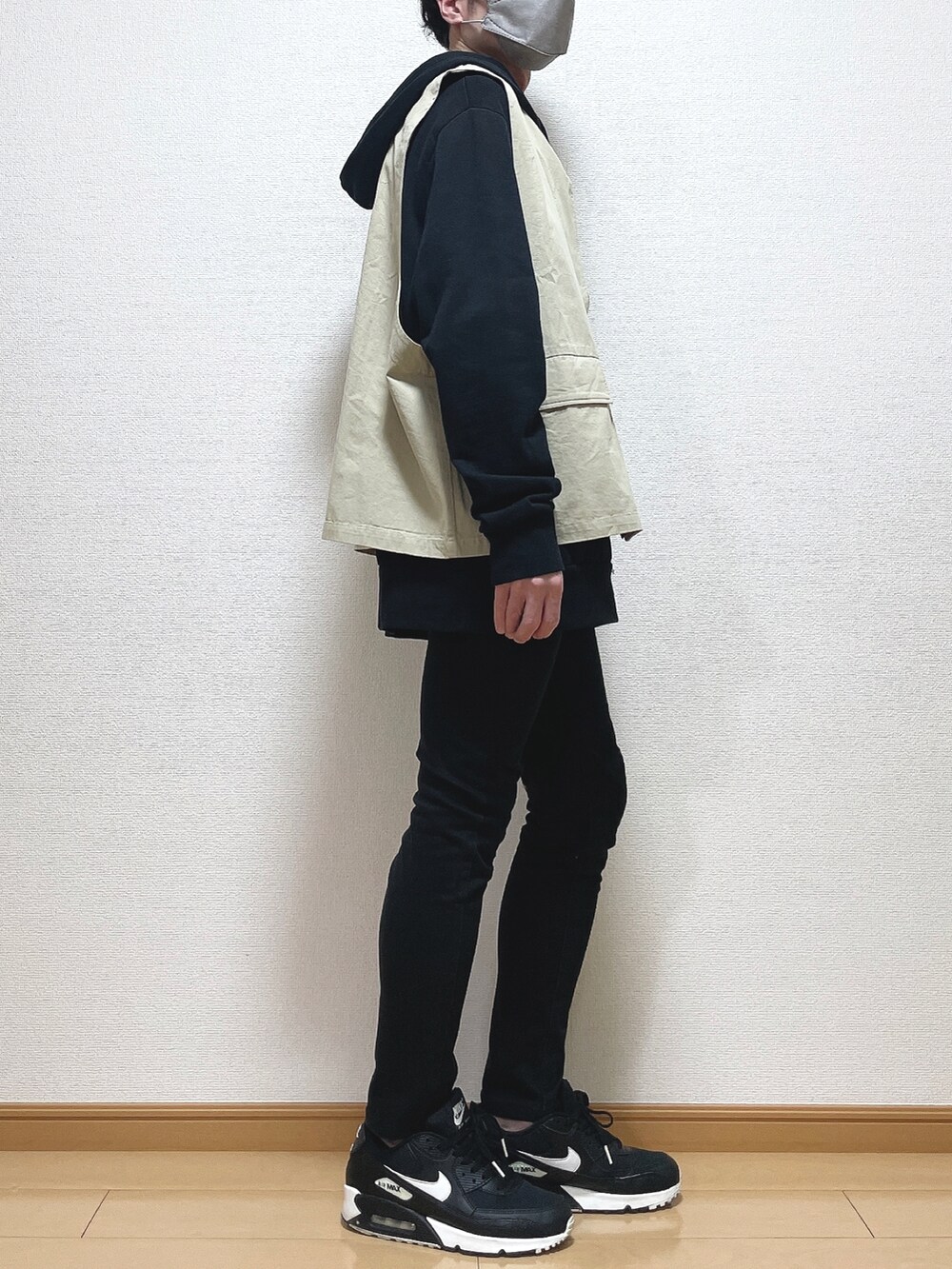 ベージュ系のベスト、ブラック系のパーカー、ブラック系のデニムパンツを着用したメンズの春コーディネートの3枚目の写真