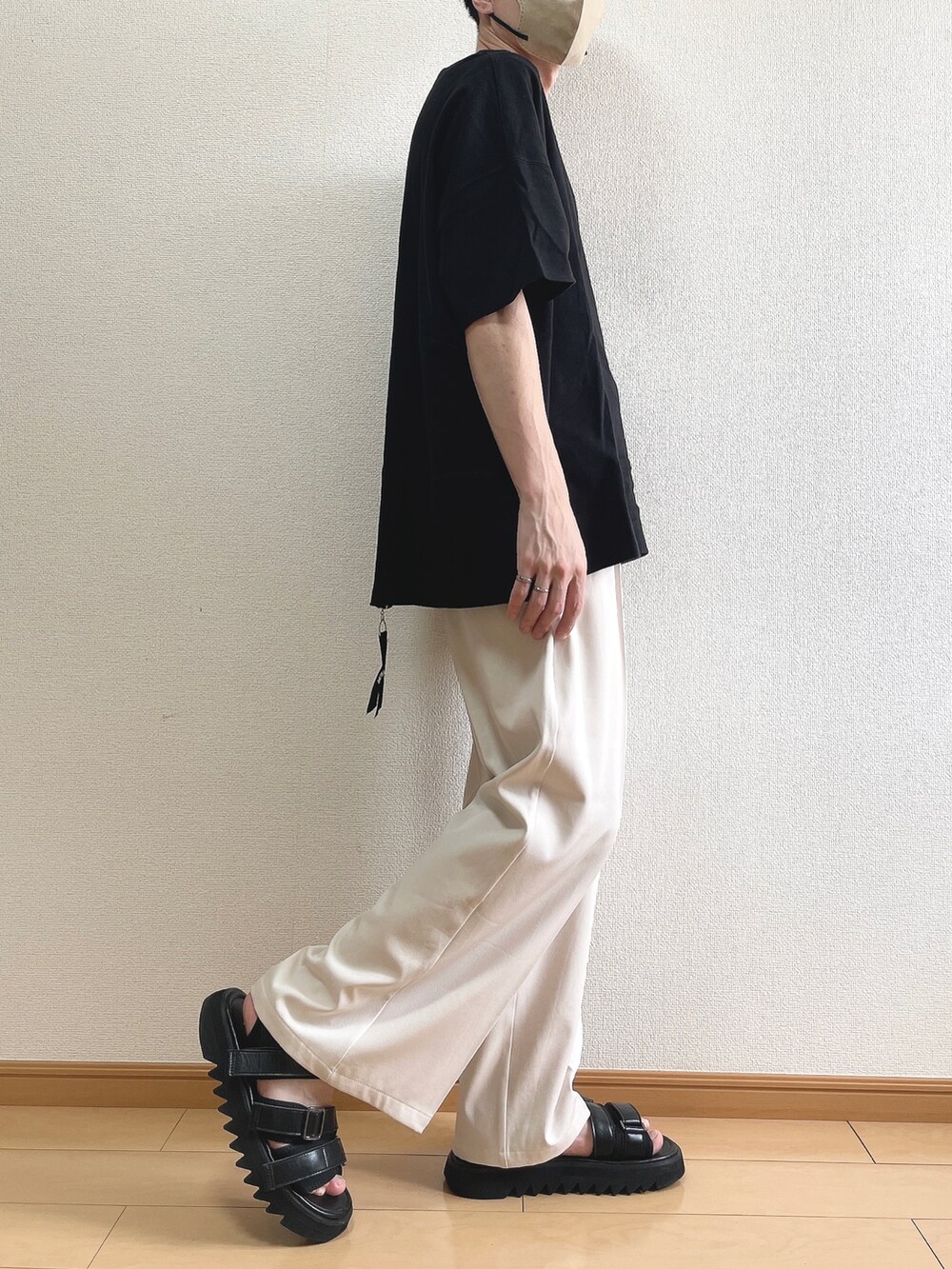 ブラック系のTシャツ/カットソー、ベージュ系のスラックス、ブラック系のサンダルを着用したメンズの夏コーディネートの2枚目の写真