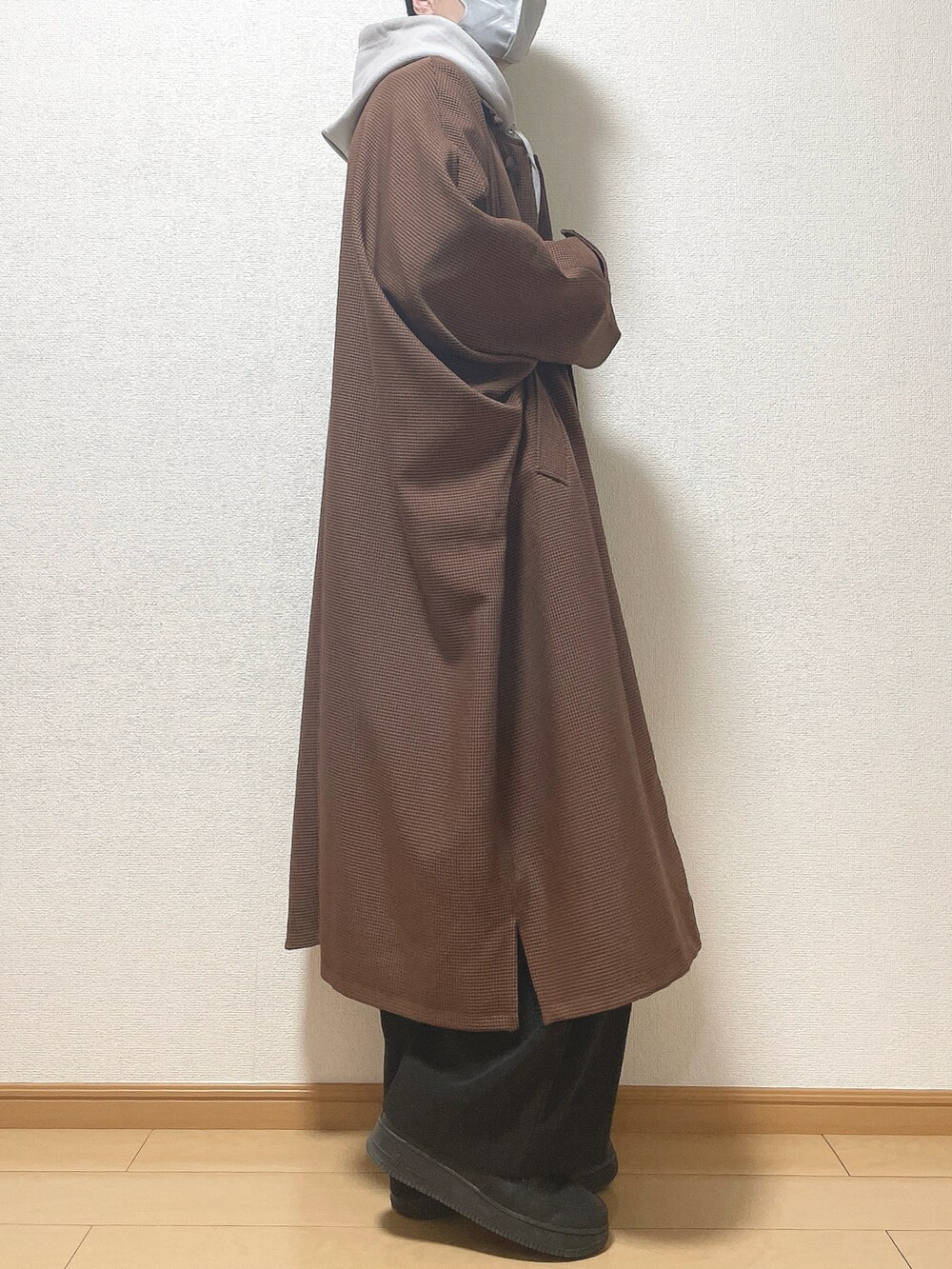 ブラウン系のステンカラーコート、グレー系のパーカー、ブラック系のその他パンツを着用したメンズの冬コーディネートの2枚目の写真