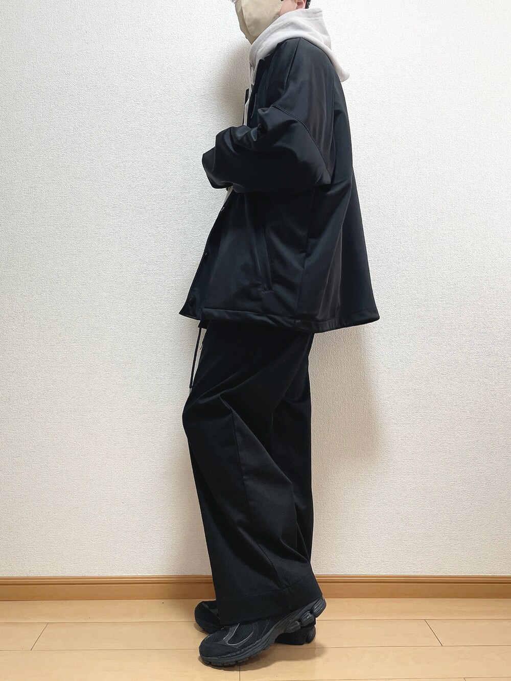 ブラック系のブルゾン、グレー系のパーカー、ブラック系のスラックスを着用したメンズの春コーディネートの3枚目の写真