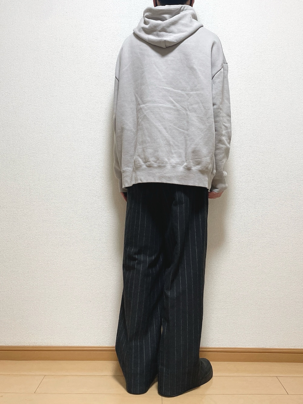 グレー系のパーカー、ブラック系のパンツ、ブラック系のスニーカーを着用したメンズの秋コーディネートの4枚目の写真